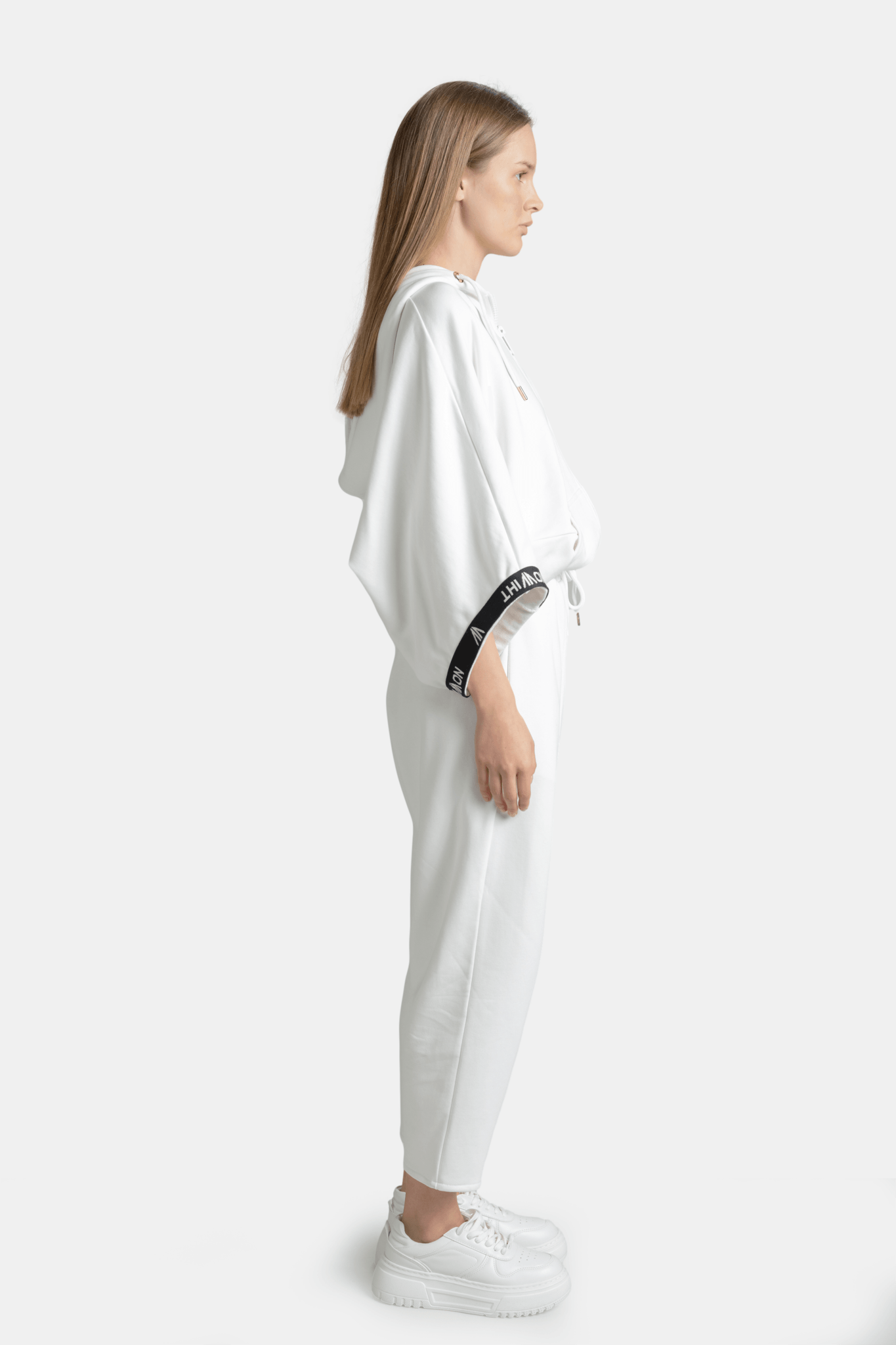 Side profile of Elif - Parachute Sleeve Tracksuit Set in White, highlighting the parachute sleeves and streamlined pants.