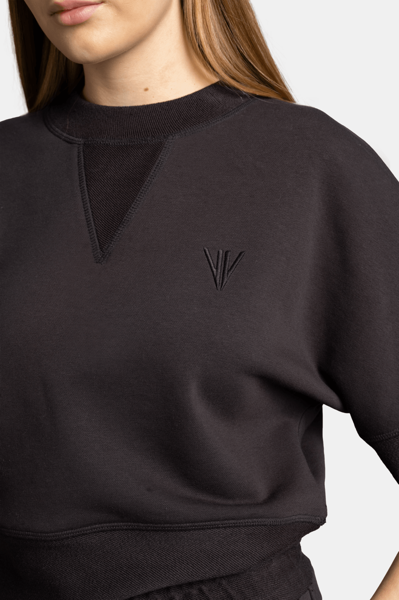 Meira - Cargo Jogger Tracksuit Set in Black, close-up of sweatshirt logo focusing on the minimalist embroidered logo on the sweatshirt, capturing the sleek design.