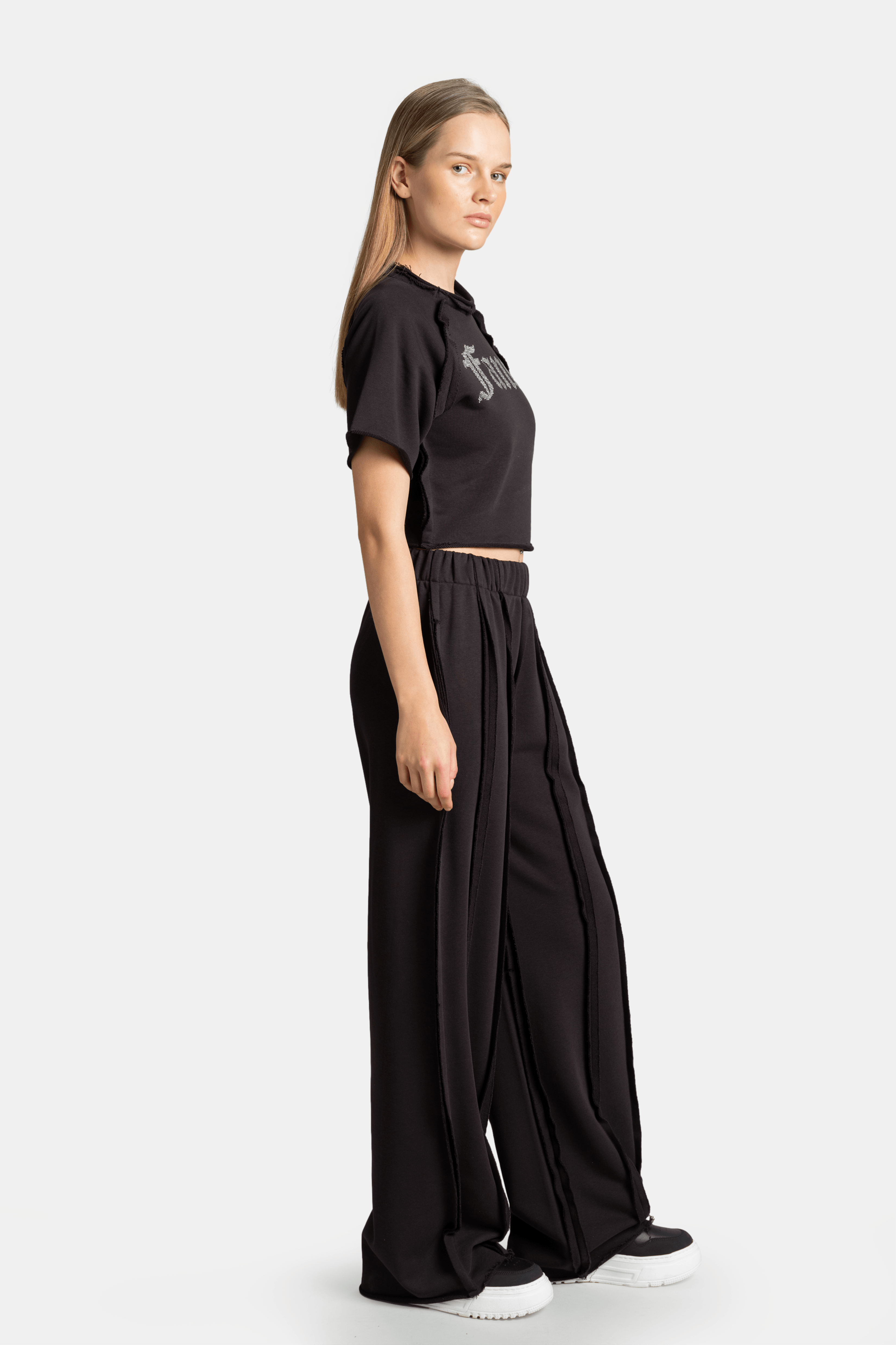 Side profile of Amira - Fancy Crop Tracksuit Set in black, featuring the cropped t-shirt and wide-leg pants with a casual fit.