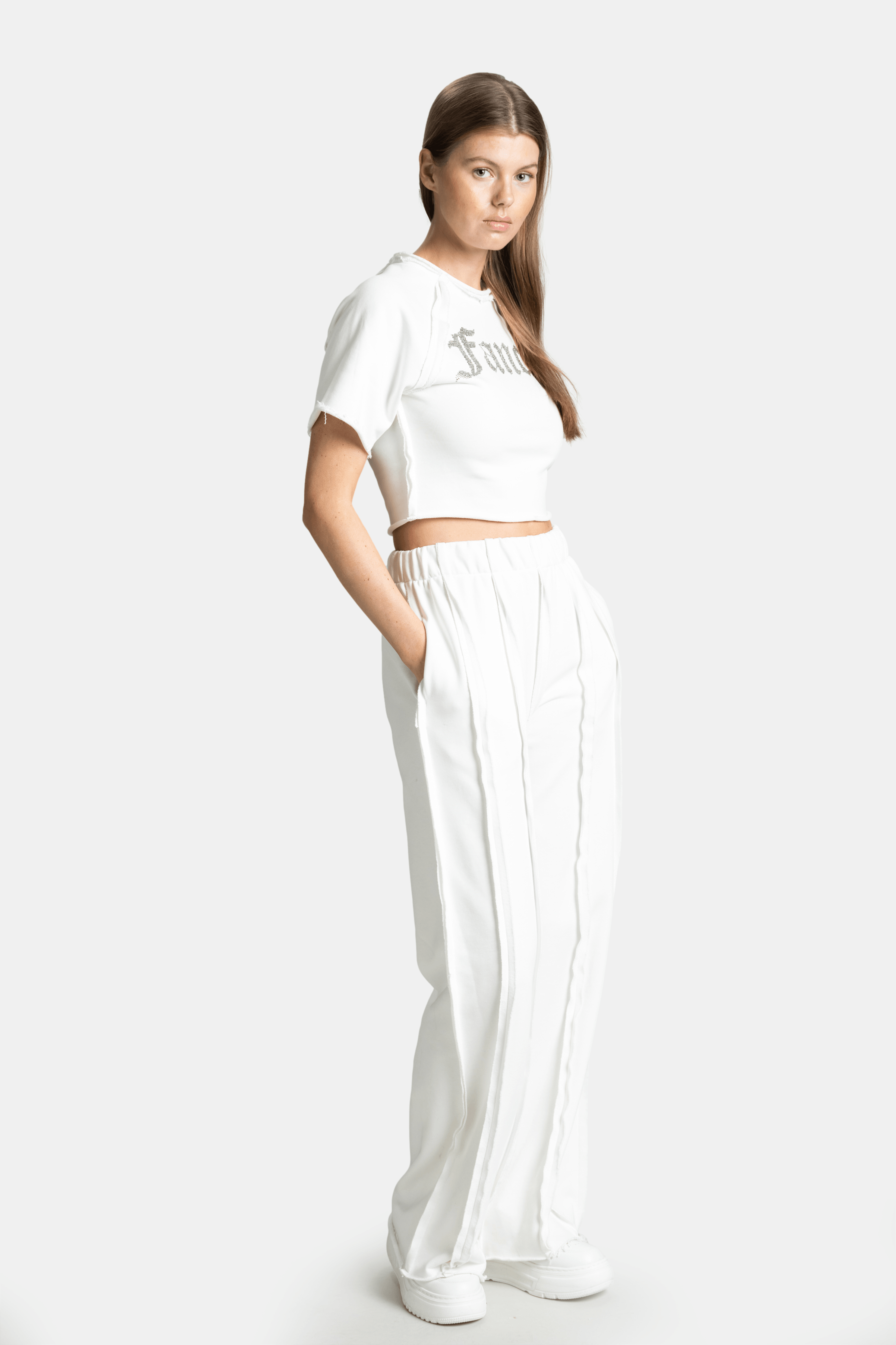 Side profile of the model in the Amira Fancy Crop Tracksuit Set in Ecru, displaying the flowy pant design.