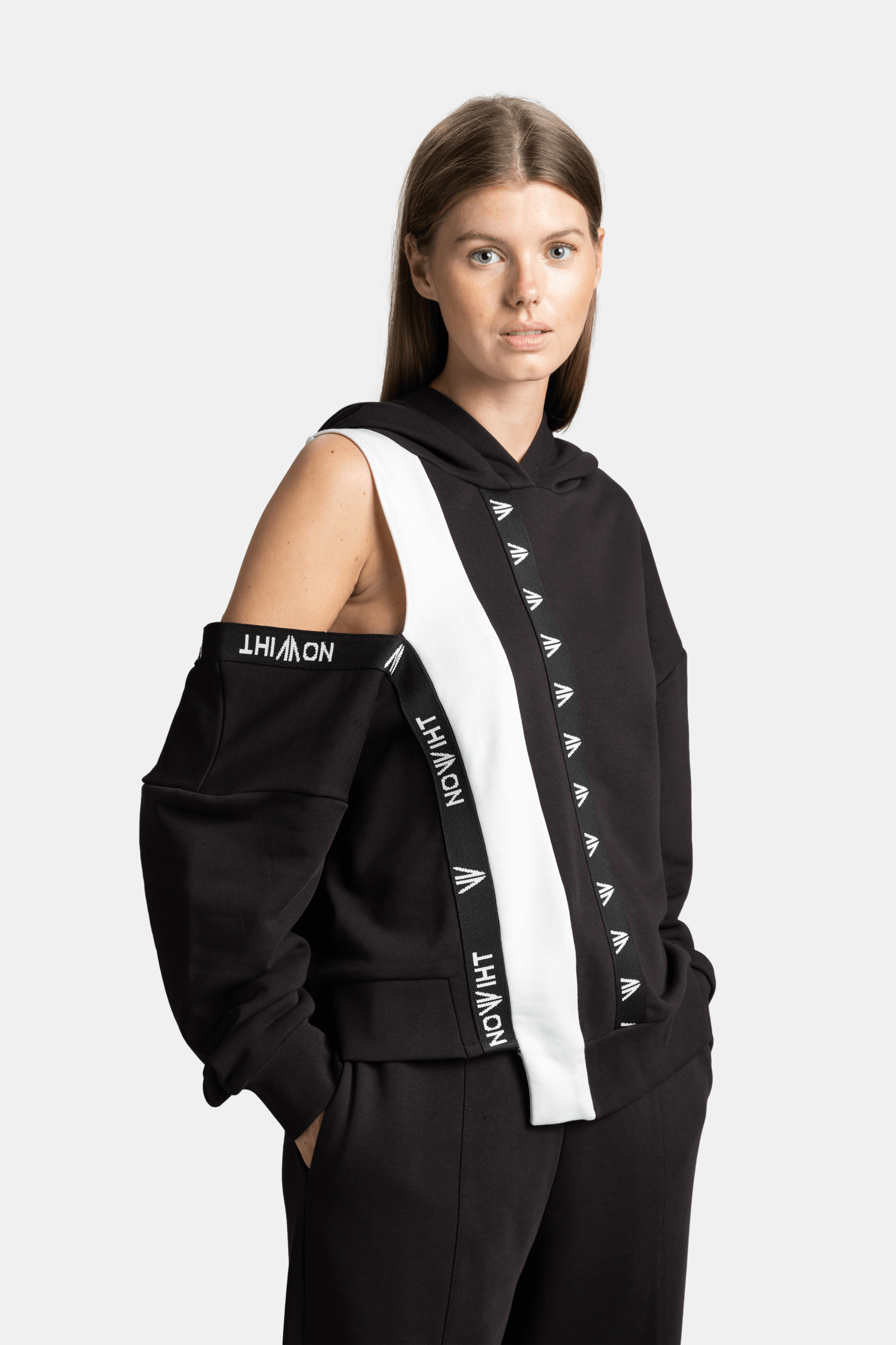 Mira - Cut Out Sleeve Tracksuit Set in Black, angled front view emphasizing the bold white stripe with Nowiht logo detail.