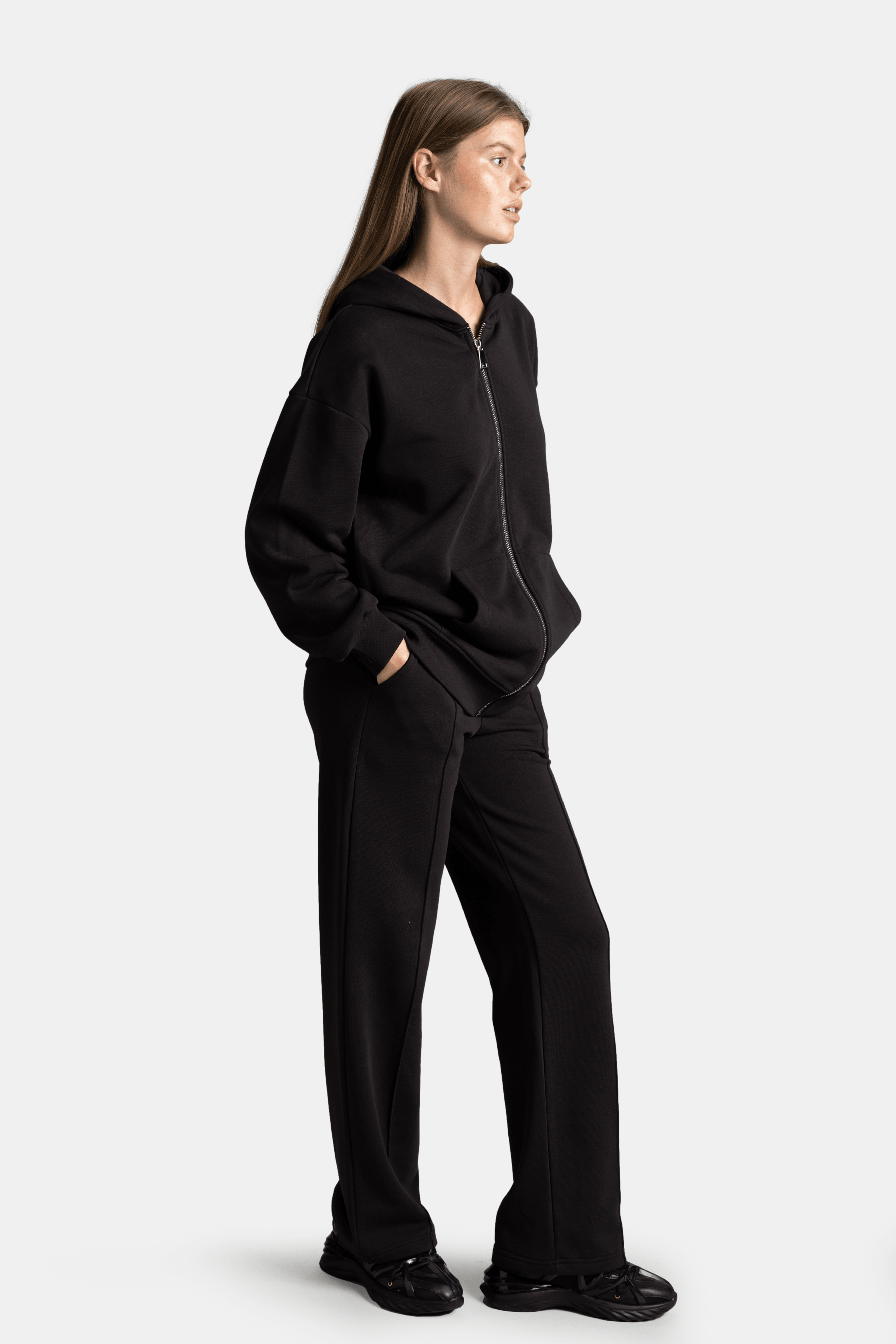 Brianna - Zipper Tracksuit Set in Black - Side profile with hands in pockets, displaying the hoodie and pants fit