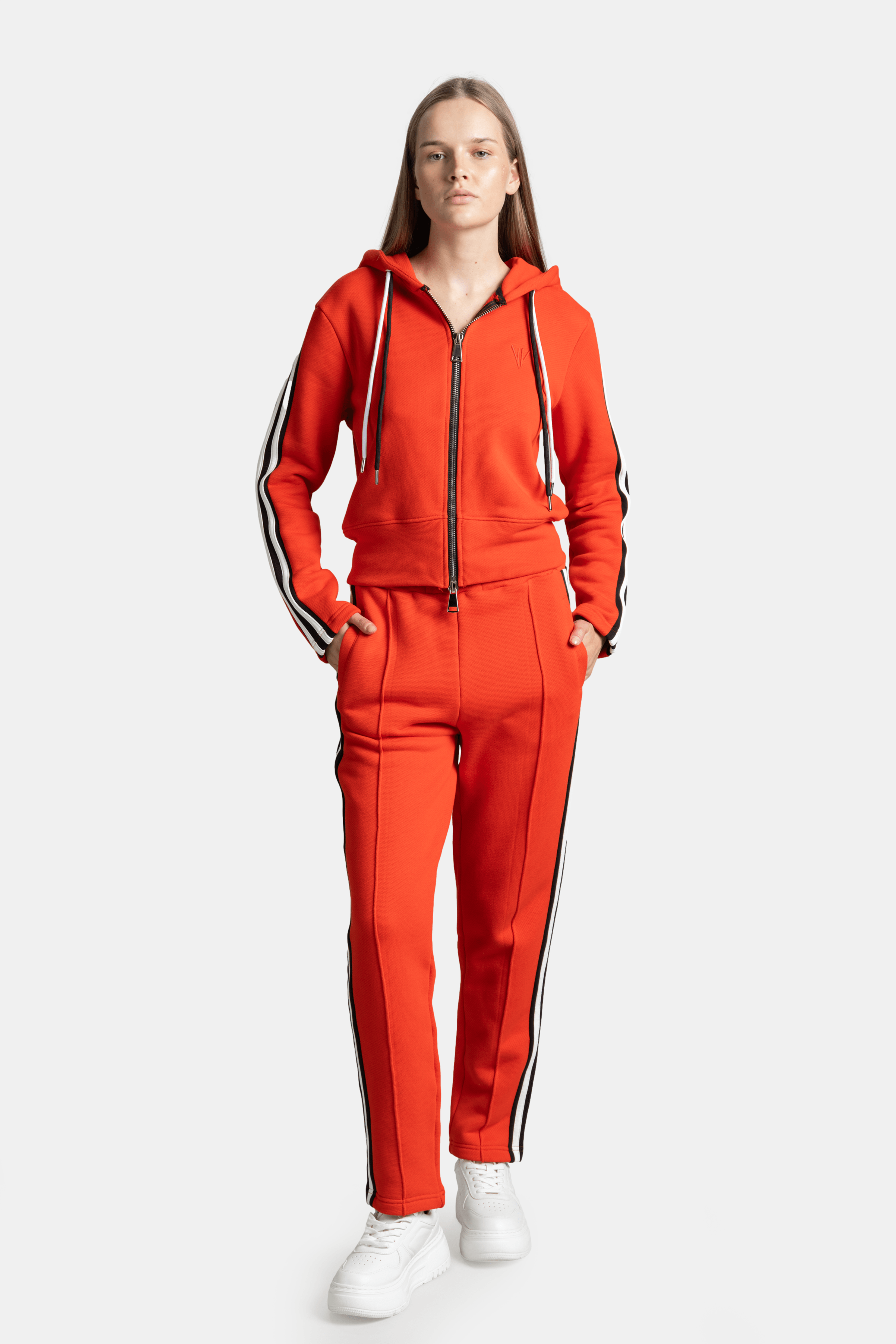 Callista - Sporty Zipper Tracksuit Set in Red, front view showing the vibrant red hoodie and pants with contrasting black and white stripes on sleeves and legs, model with hands in pockets.