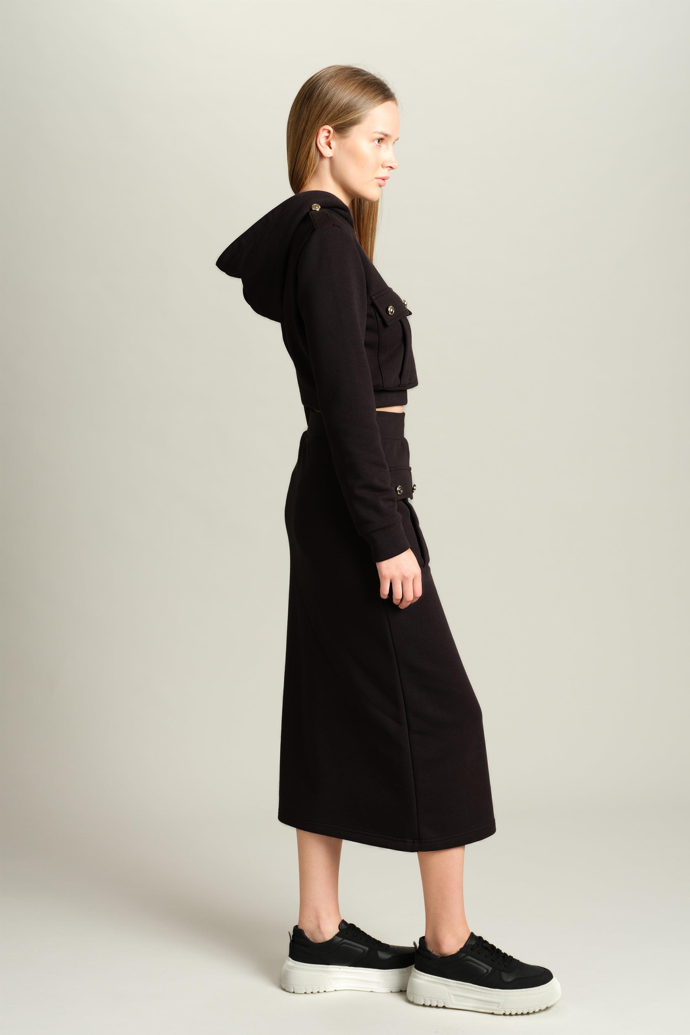 Capri - Pocket Detail Skirt Set in Black, side profile view highlighting the elegant structure of the skirt and top with pocket details, model standing in a composed posture.