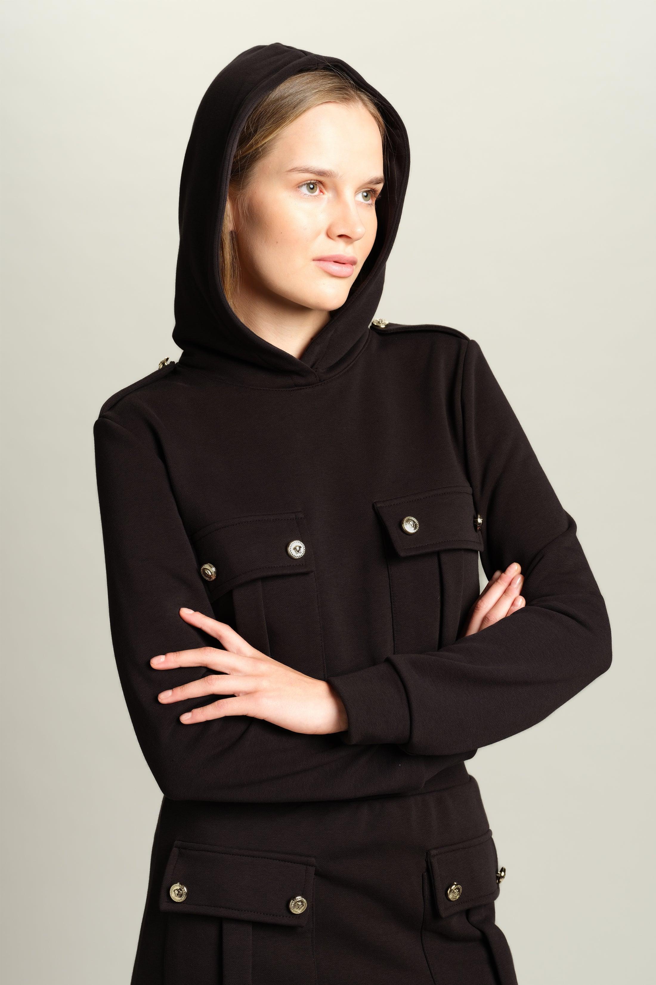 Capri - Pocket Detail Skirt Set in Black, close-up of the hooded top’s front pockets and button details, model with arms crossed, reflecting a modern casual style.