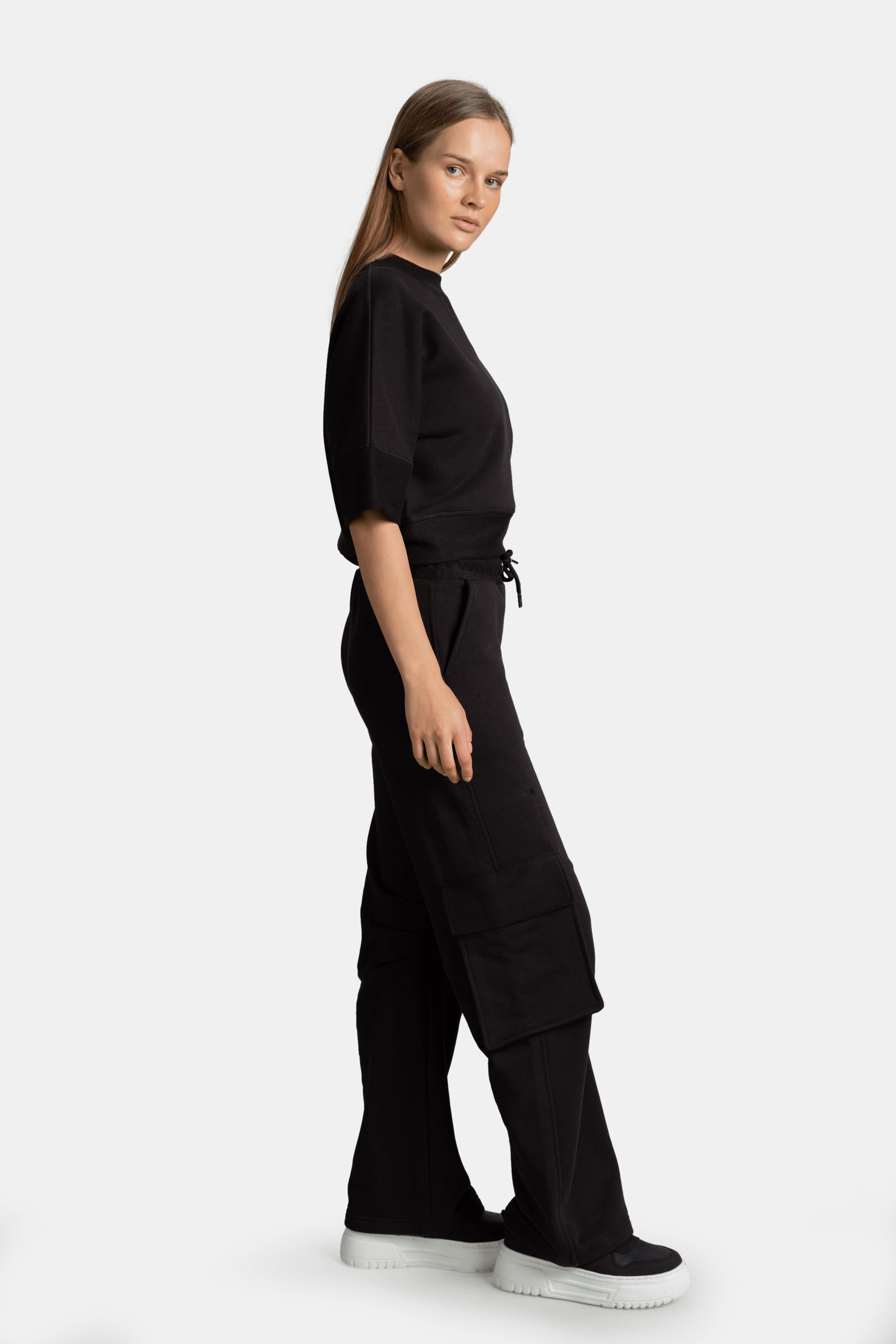 Meira - Cargo Jogger Tracksuit Set in Black, side view displaying the model's profile, focusing on the modern fit and the distinctive cargo pockets on the jogger.