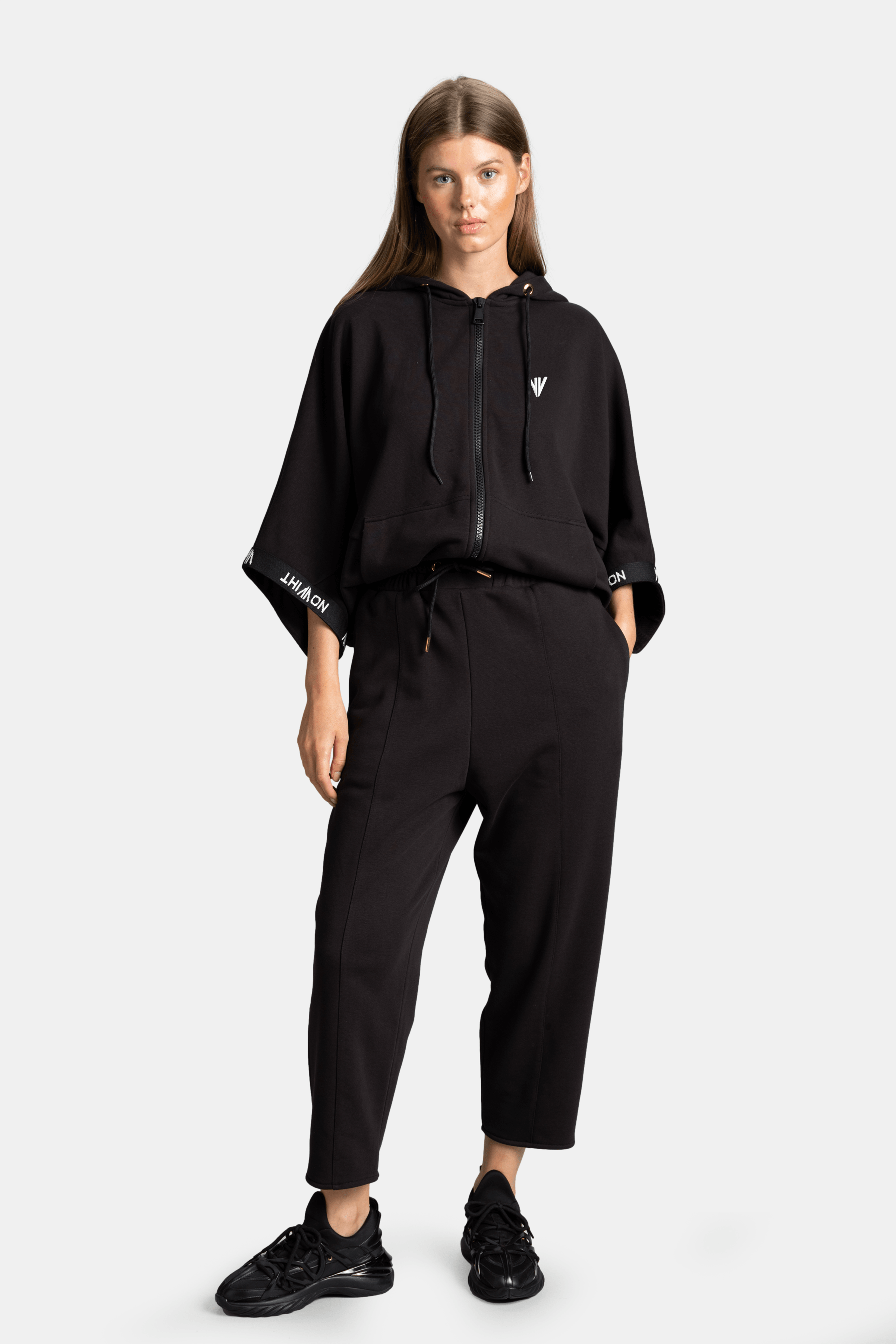 Model wearing black parachute sleeve tracksuit set front view with hands in pockets