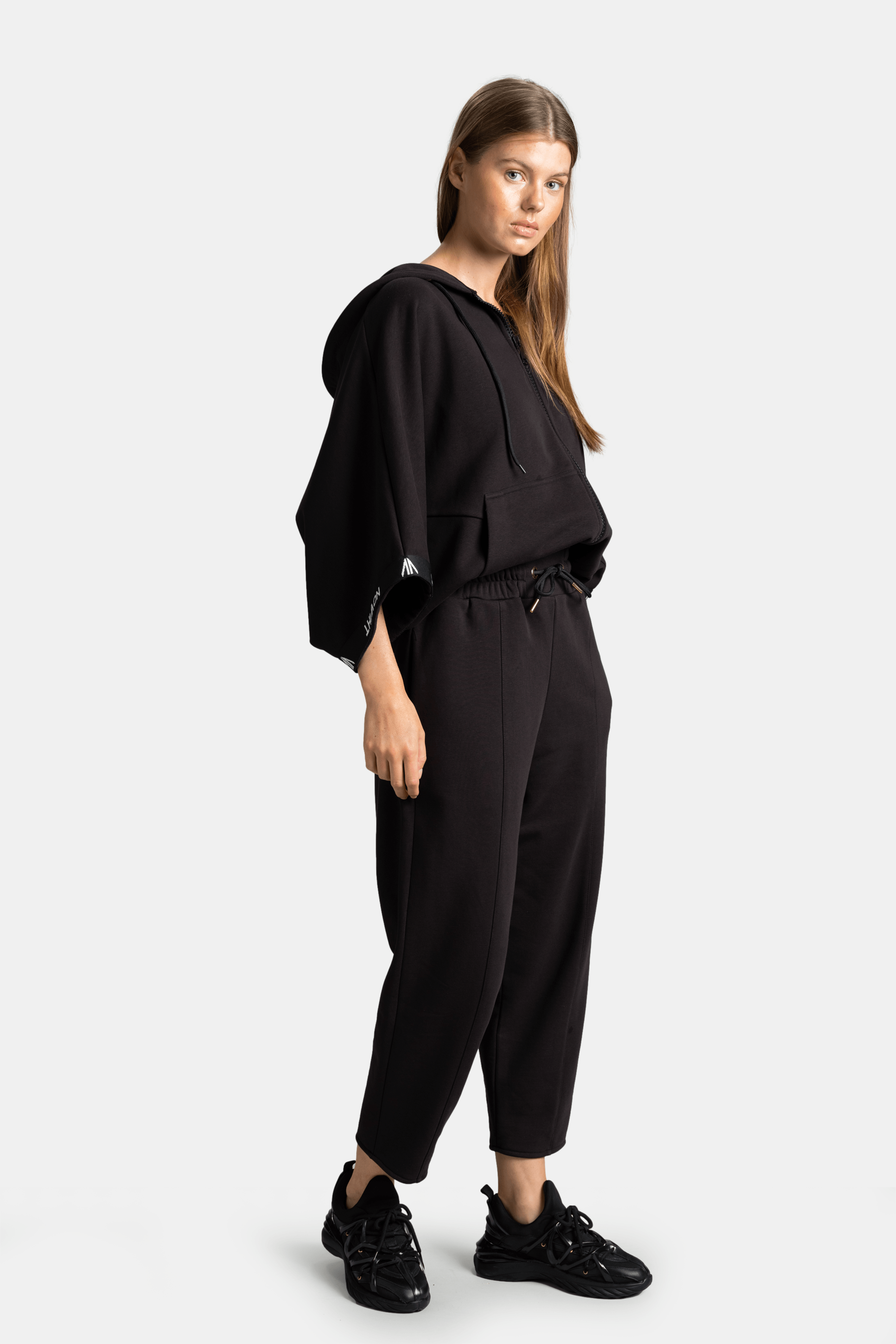 Model wearing black parachute sleeve tracksuit set side view with relaxed pose