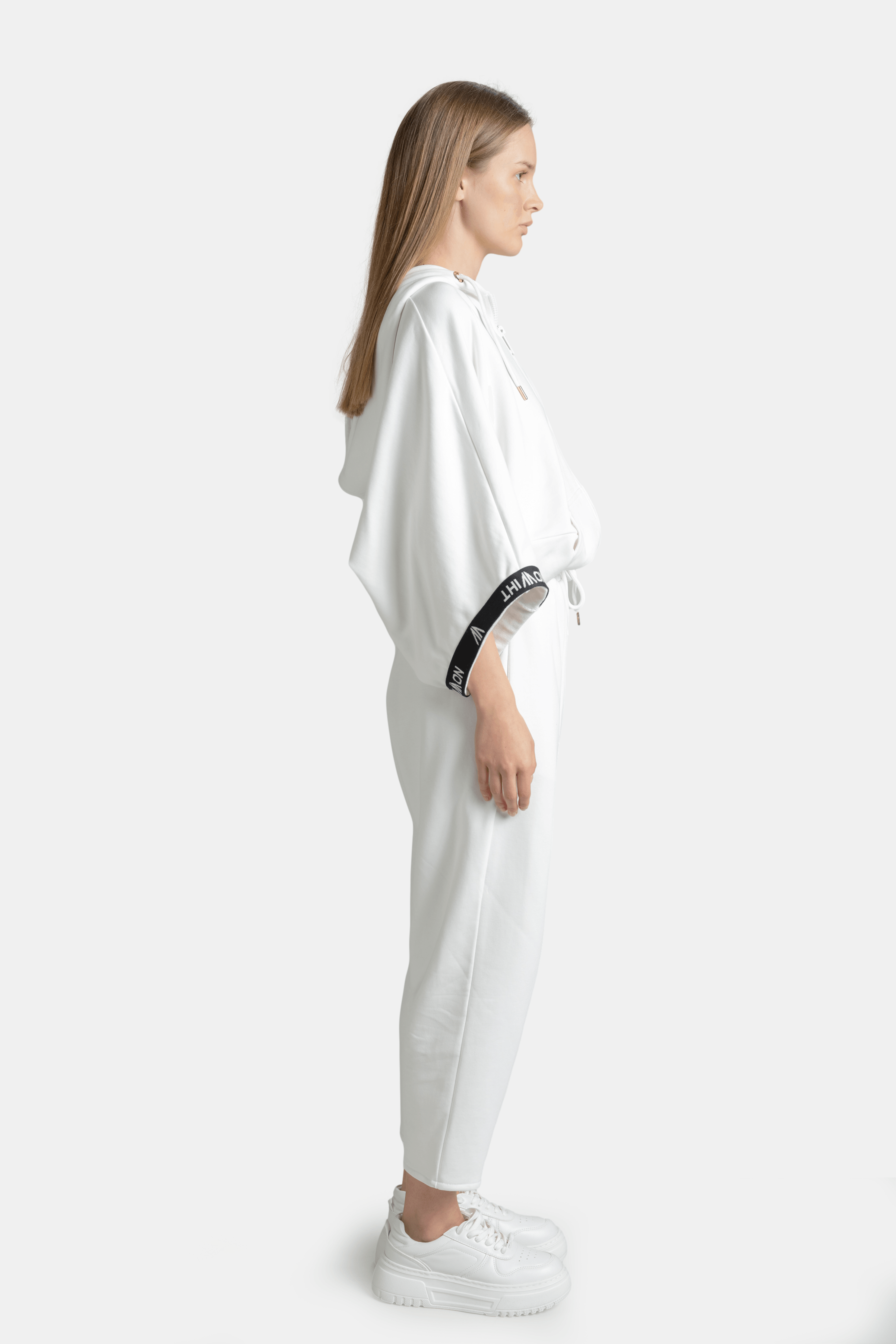 Side profile of Elif - Parachute Sleeve Tracksuit Set in White, highlighting the parachute sleeves and streamlined pants.