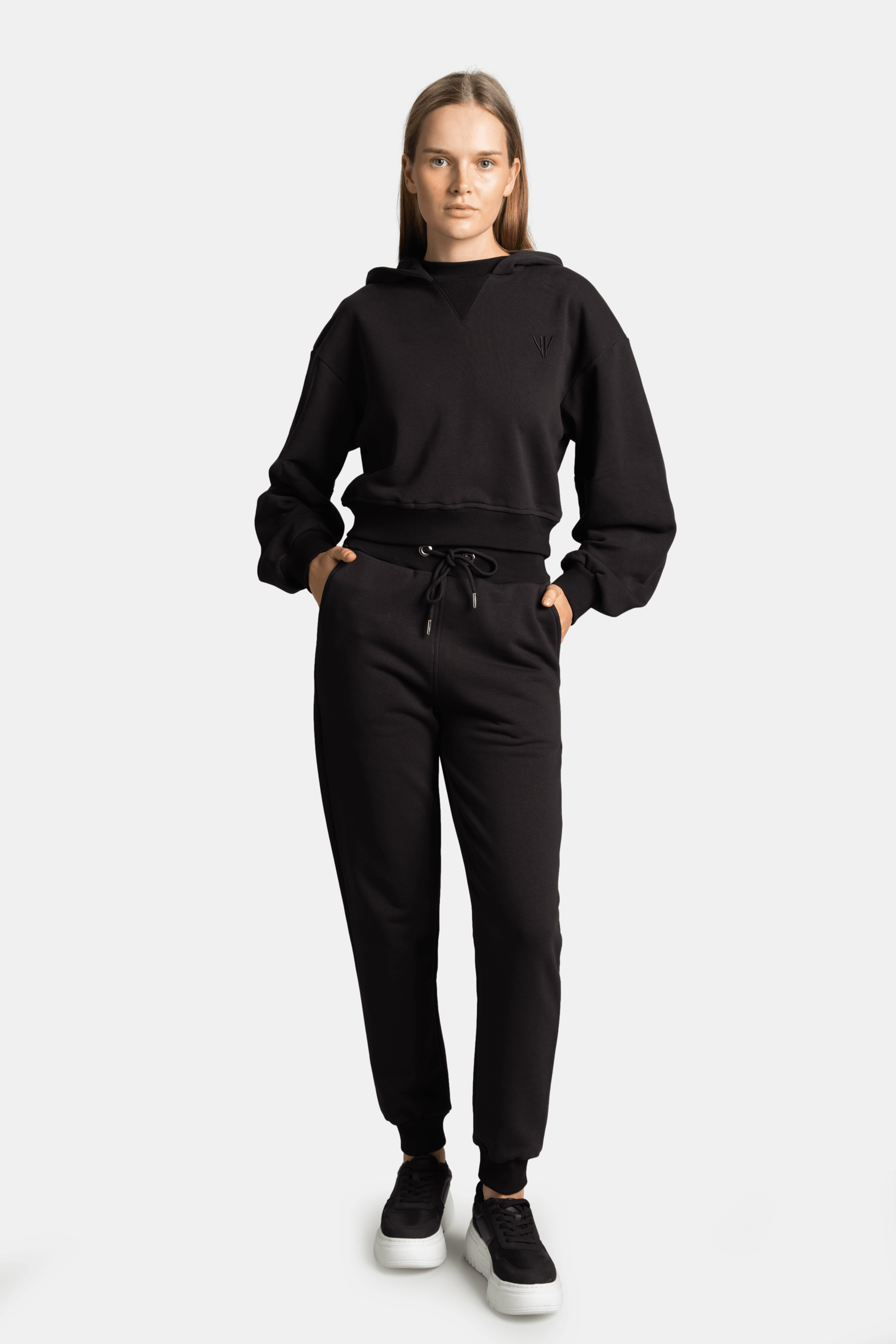 Front view of model wearing the Lilot Tone on Tone black tracksuit set with cropped hoodie and drawstring pants