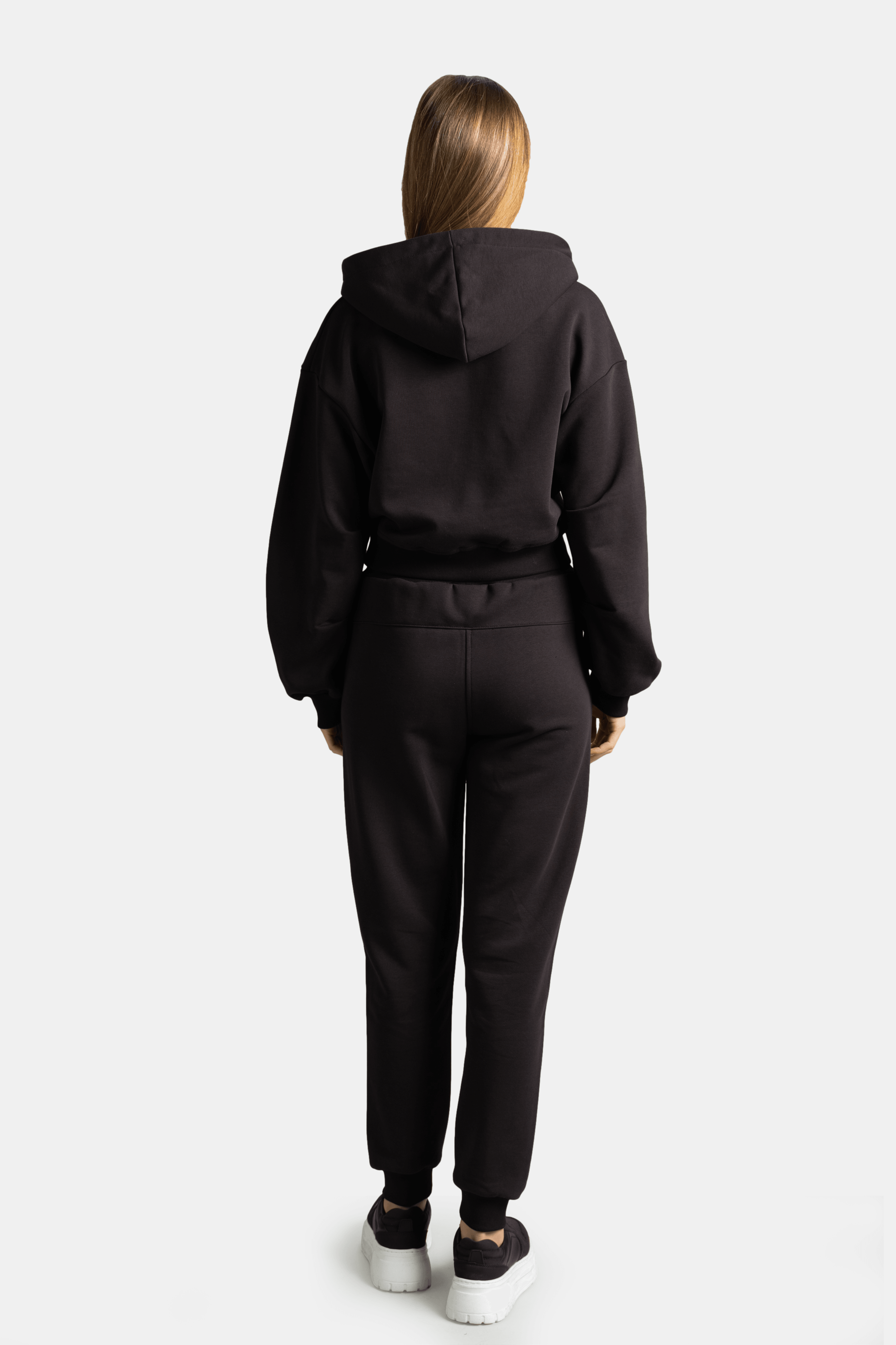 Back view of model in Lilot Tone on Tone black tracksuit, highlighting the relaxed fit of the hoodie and pants