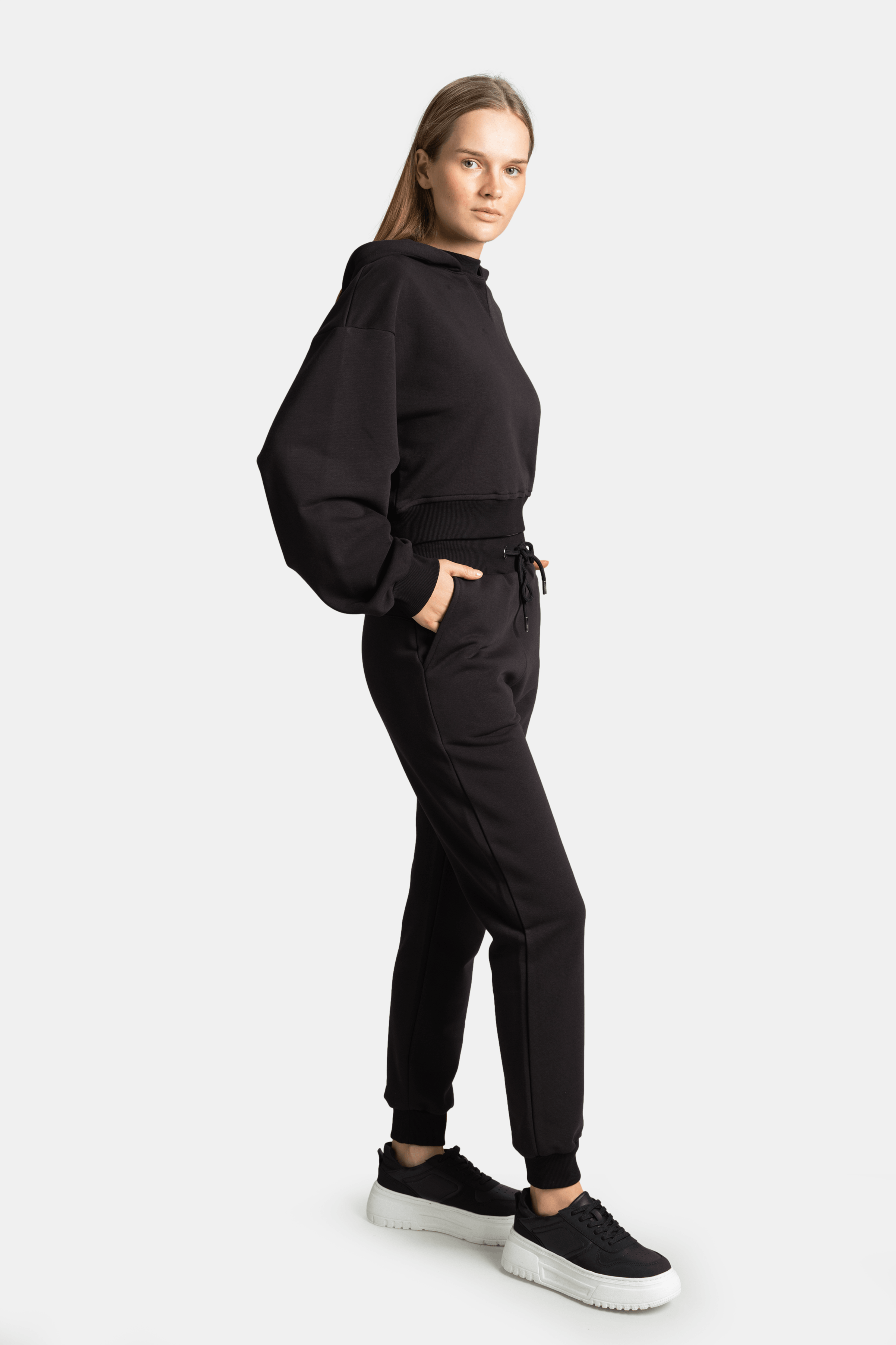 Side profile of model in Lilot Tone on Tone black tracksuit, showing off the hoodie silhouette and comfortable jogger pants