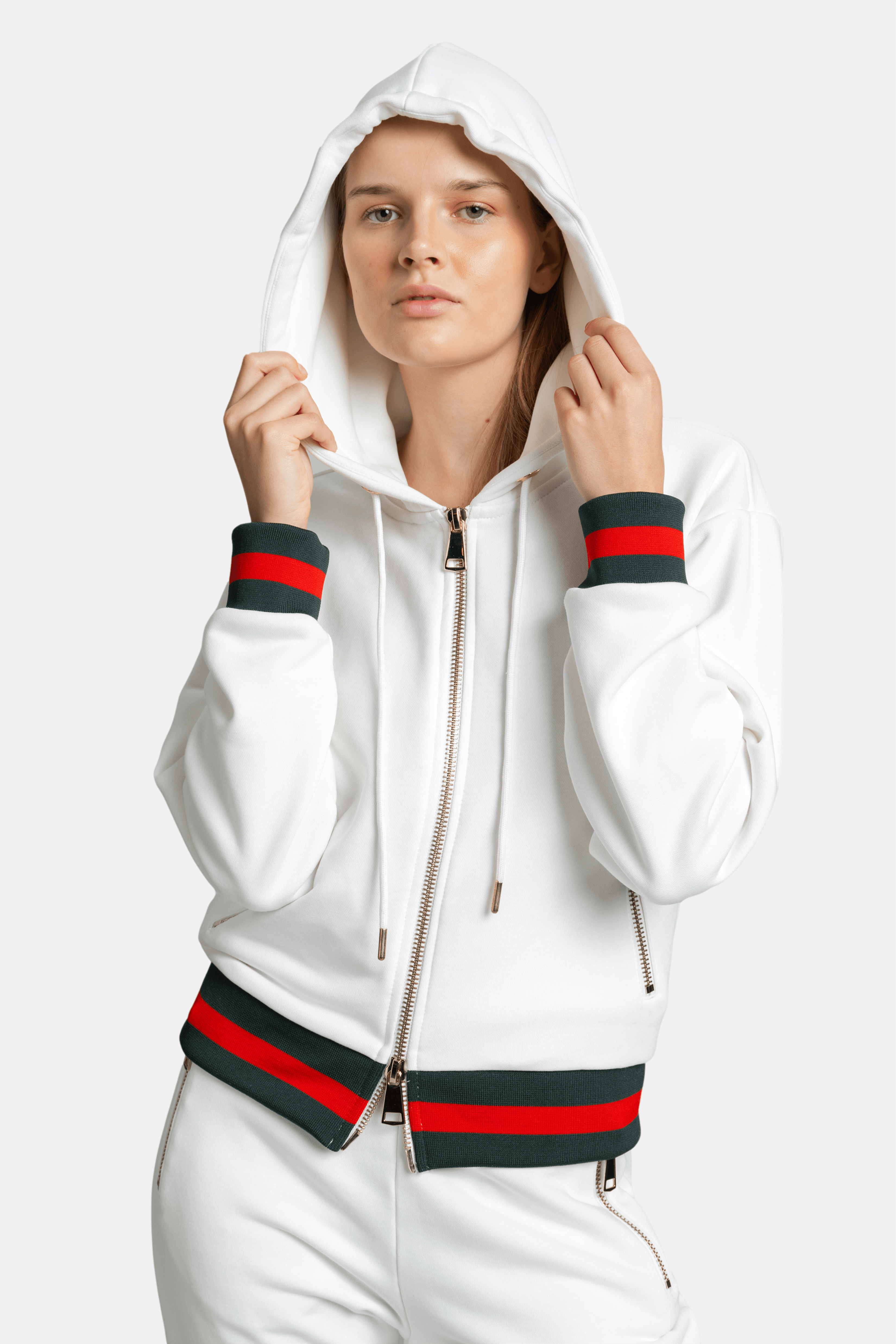 Front close-up of model holding hood in white Destiny striped zip hoodie tracksuit set with green and red striped cuffs