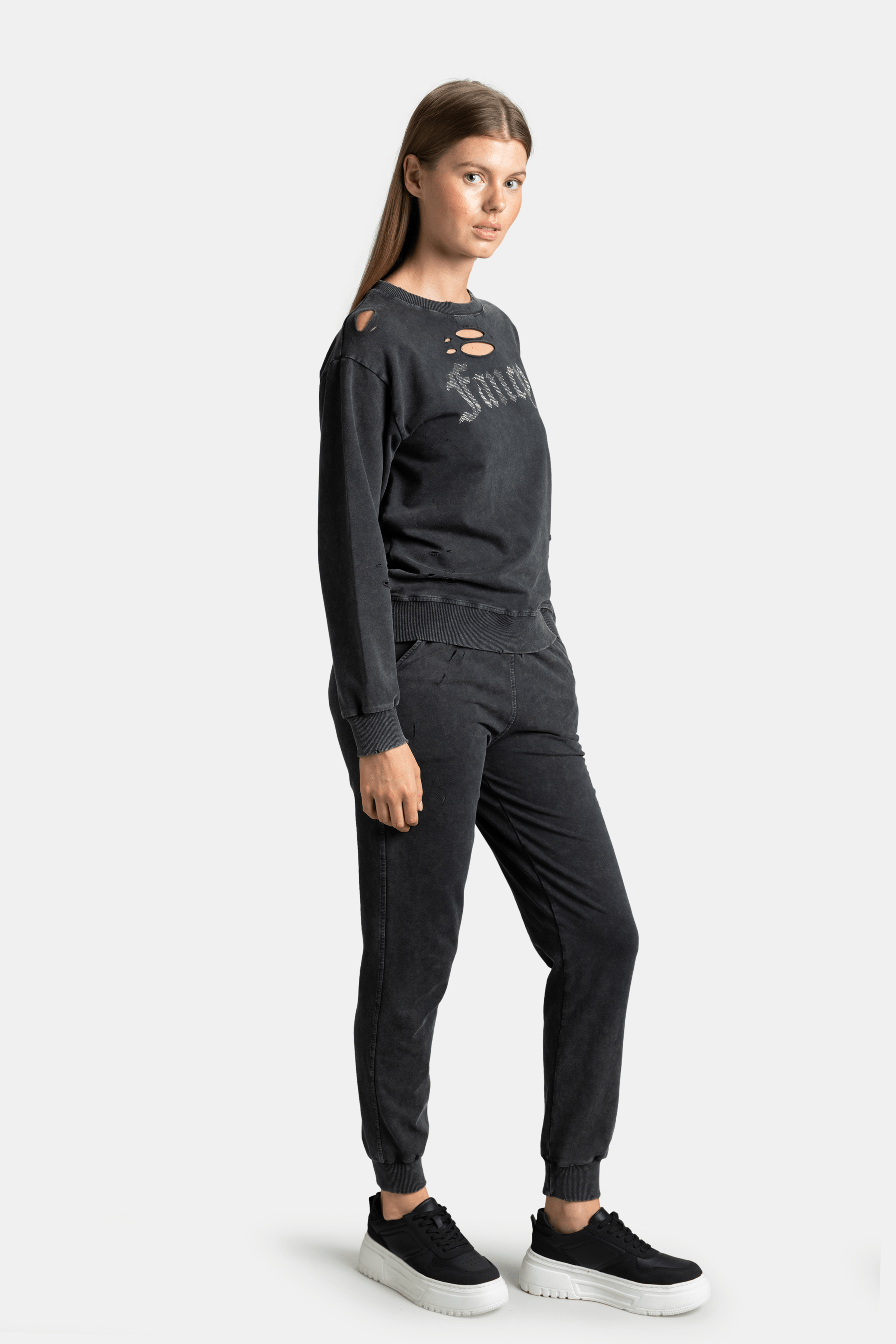 Side profile of distressed black sweatshirt with 'Fancy' text and joggers, showcasing urban streetwear appeal, comfortable and fashionable loungewear set.