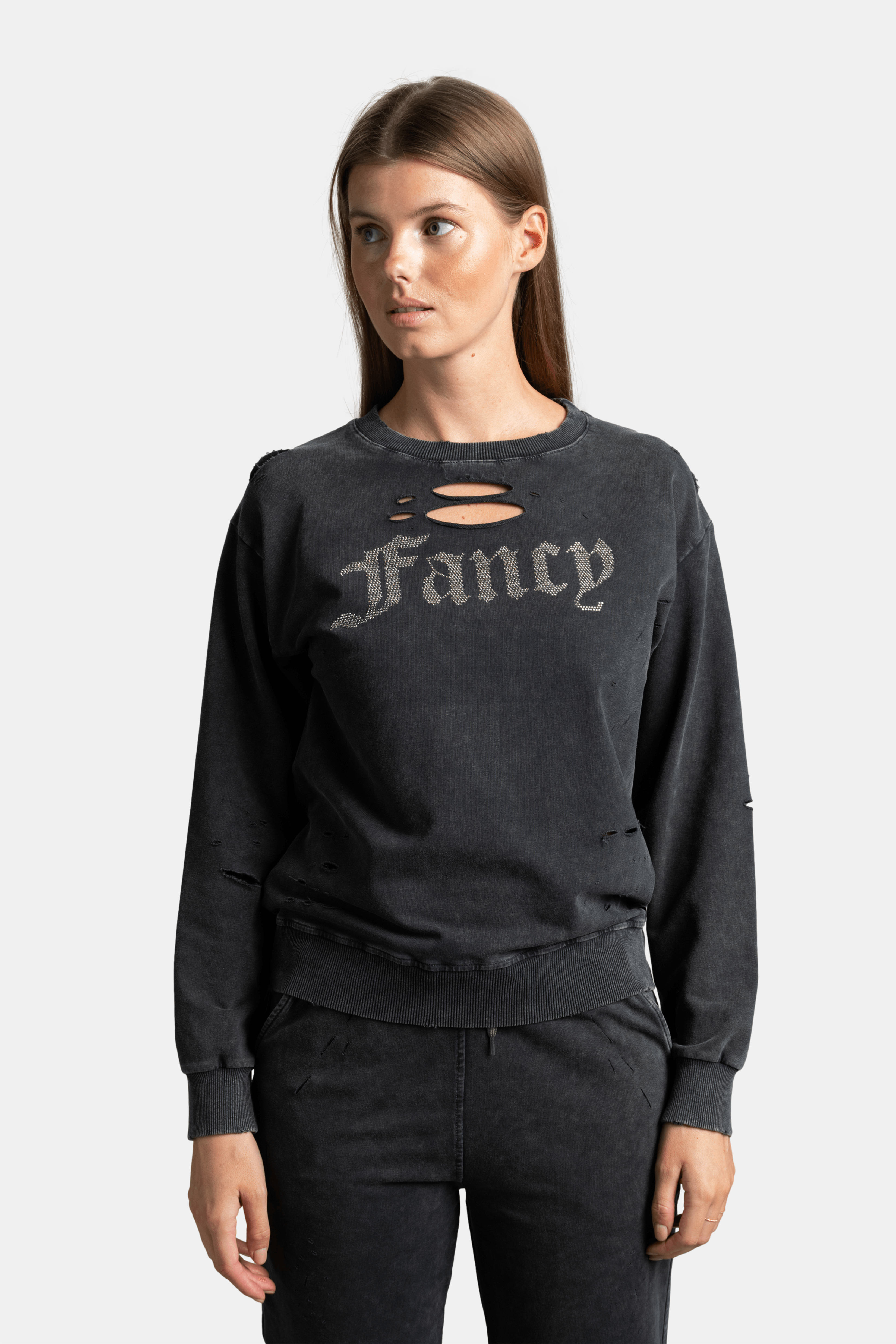 Model in black distressed sweatshirt and joggers set with 'Fancy' text, embodying effortless street style for everyday comfort and fashion.