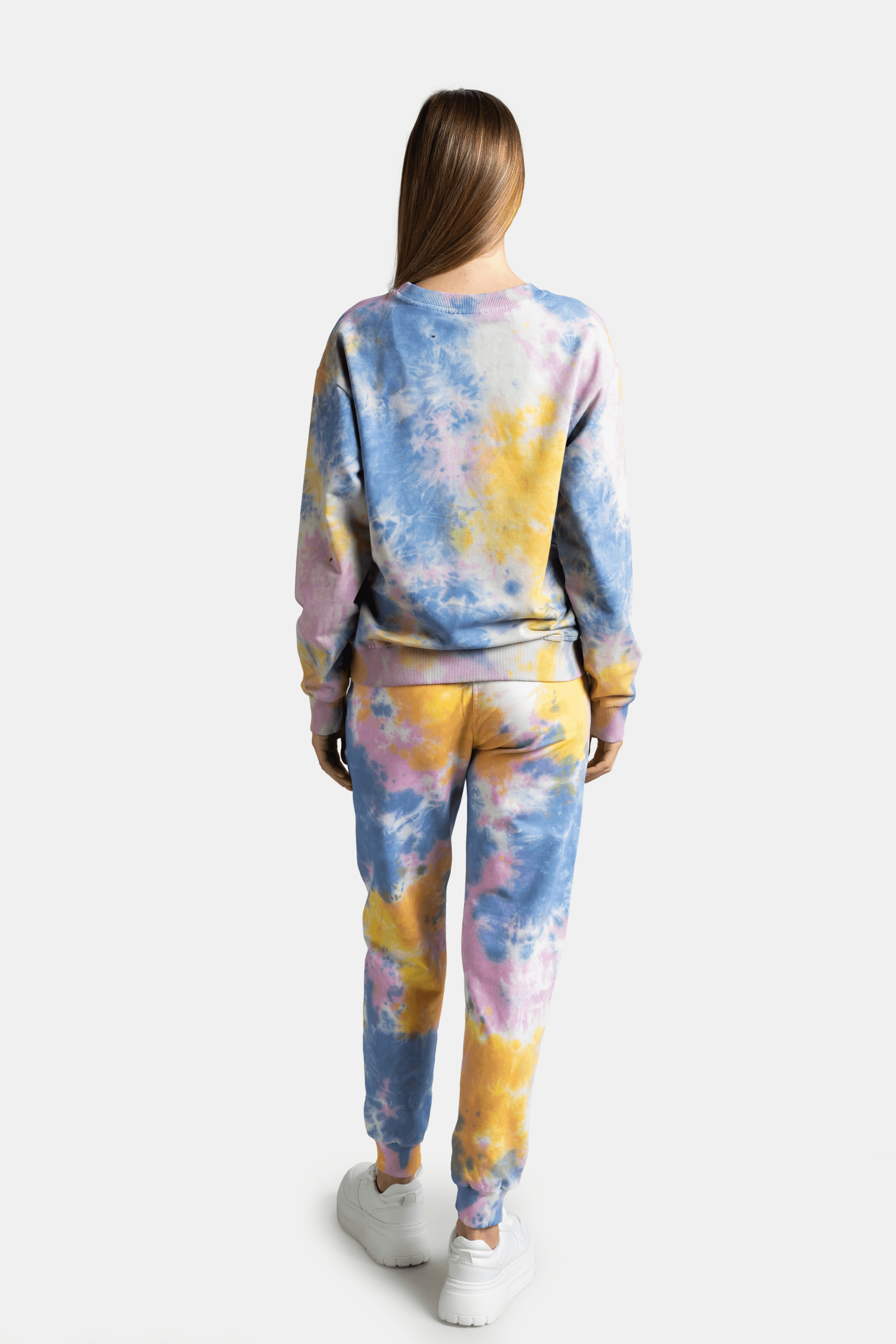 Model in back view showcasing the tie-dye design in pastel pink, blue, and yellow on the tracksuit set.