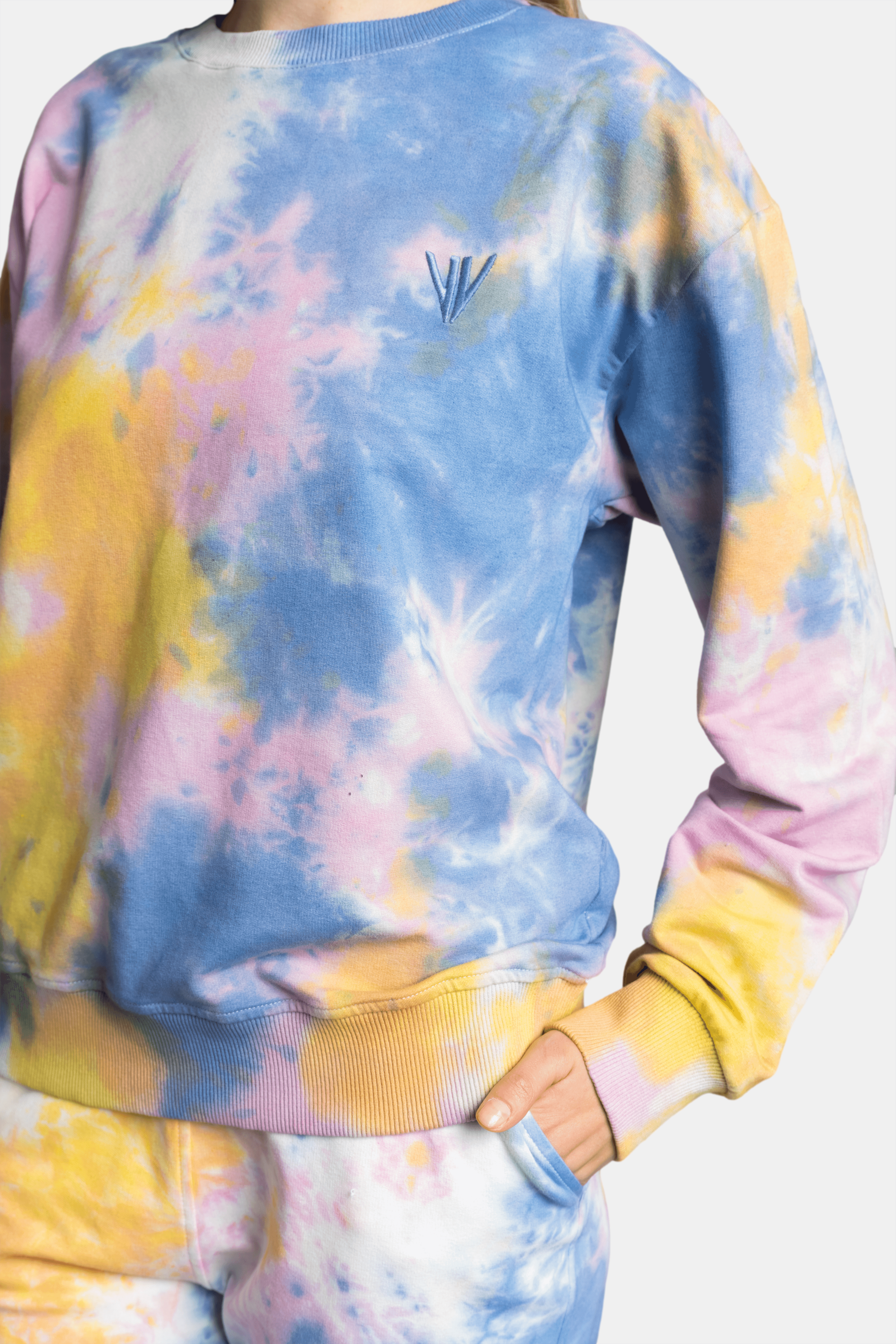 Model standing with hands in pockets, displaying the tie-dye tracksuit with pastel hues.