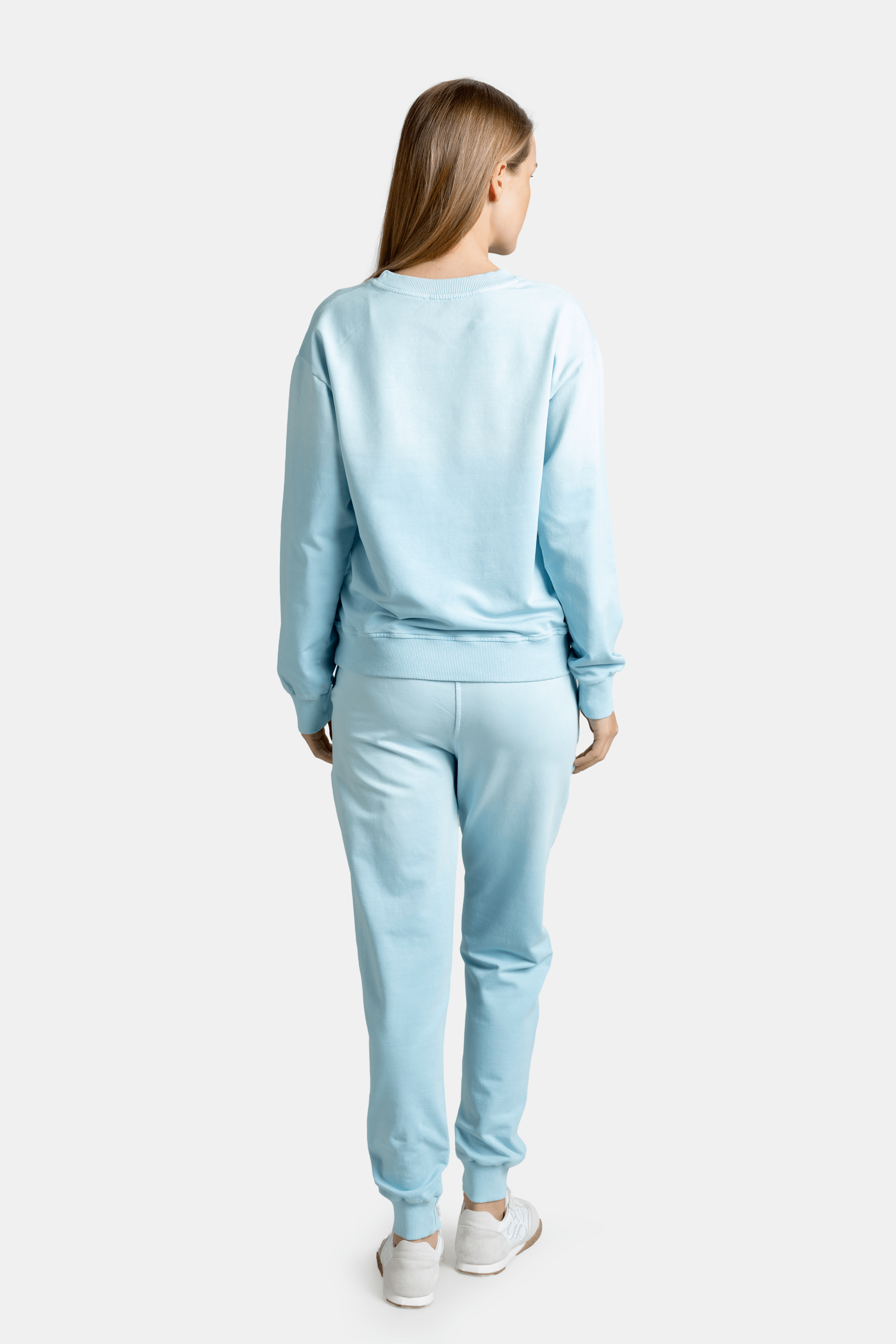 Rear view of a woman wearing a light blue sweatshirt and joggers, highlighting the back design.