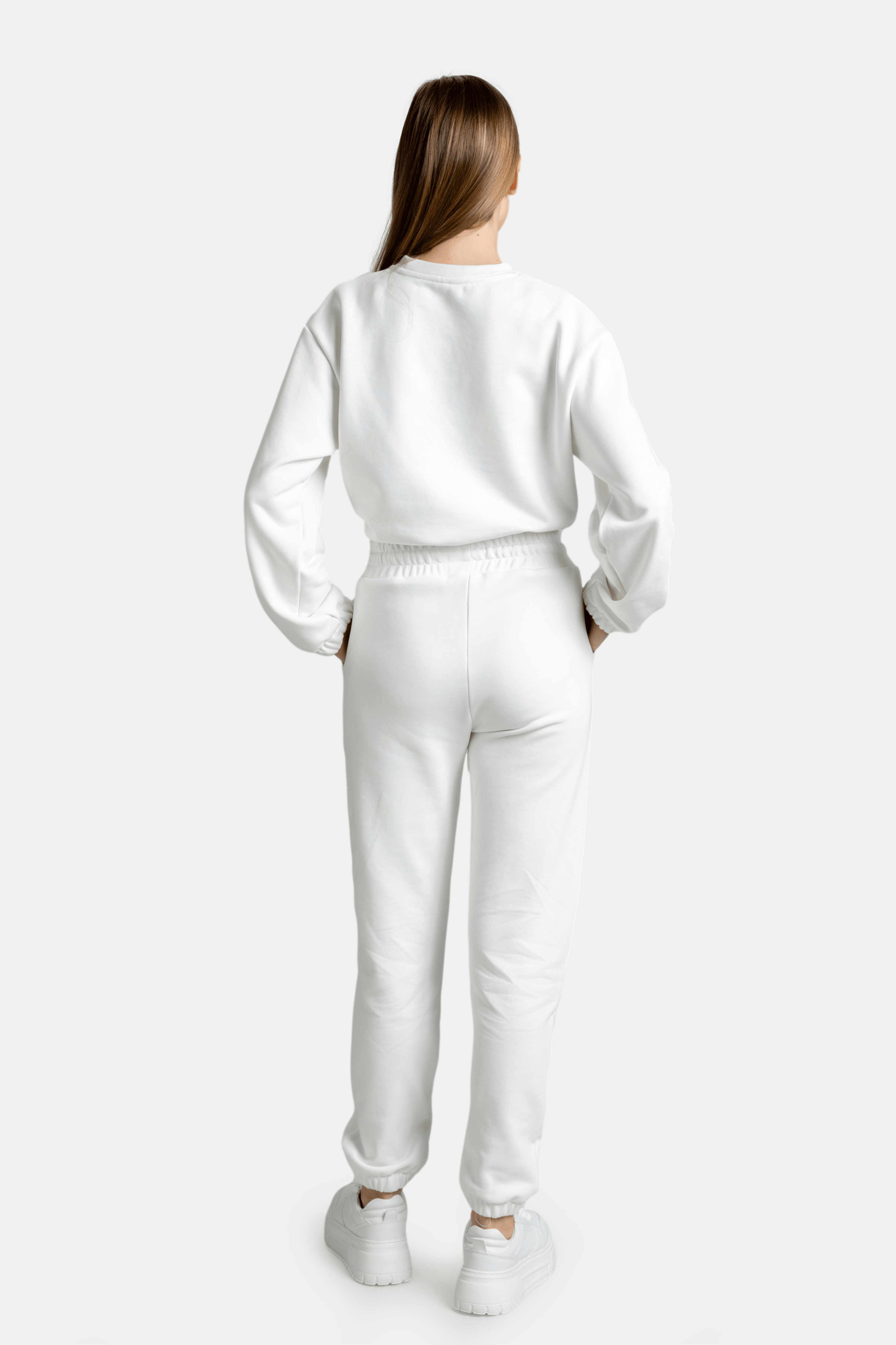 Back view of the model in the white Nowiht tracksuit set, highlighting the elastic waistband and cuffs for comfort.