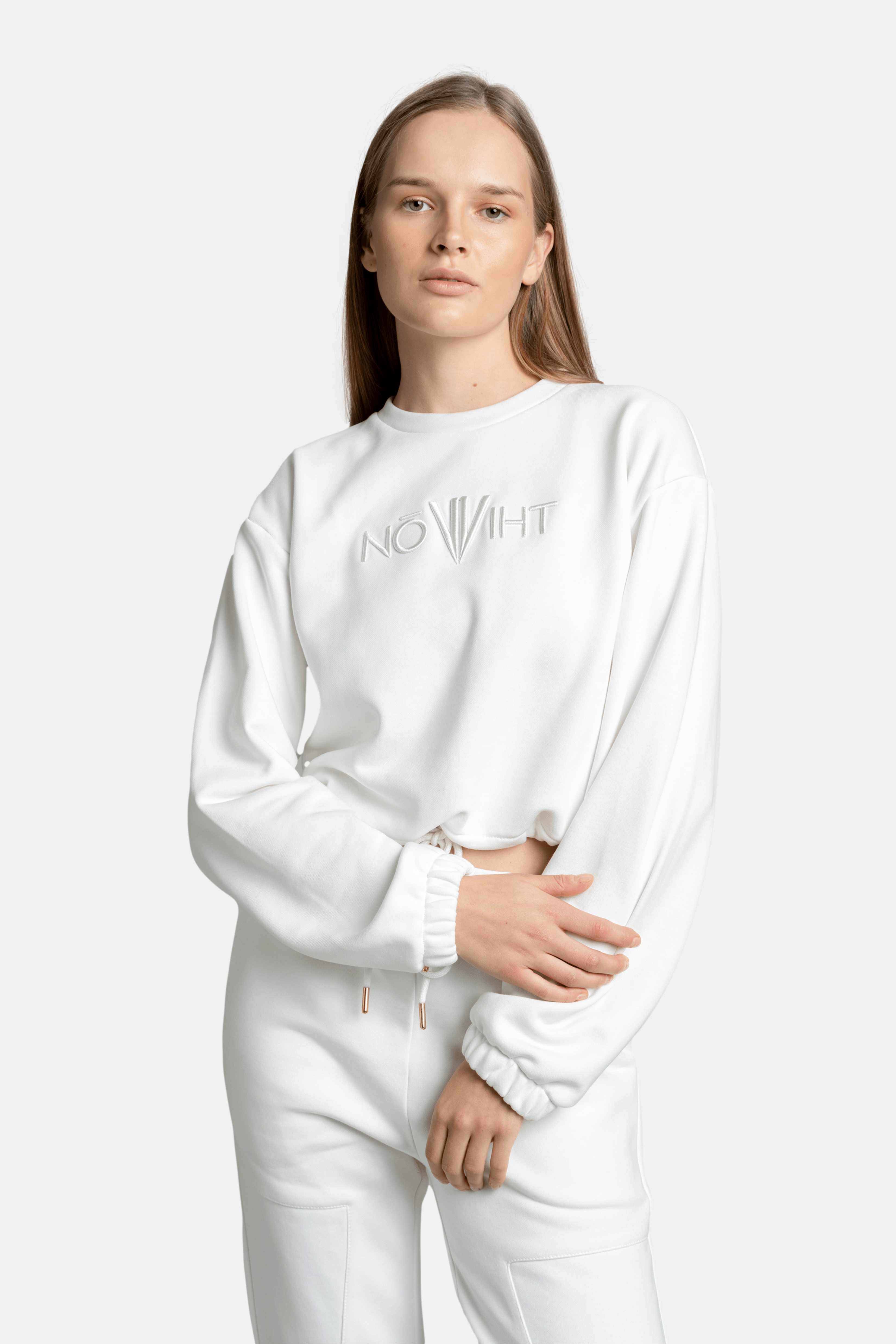 Close-up of the model wearing the white Nowiht sweatshirt, focusing on the logo detail on the chest.