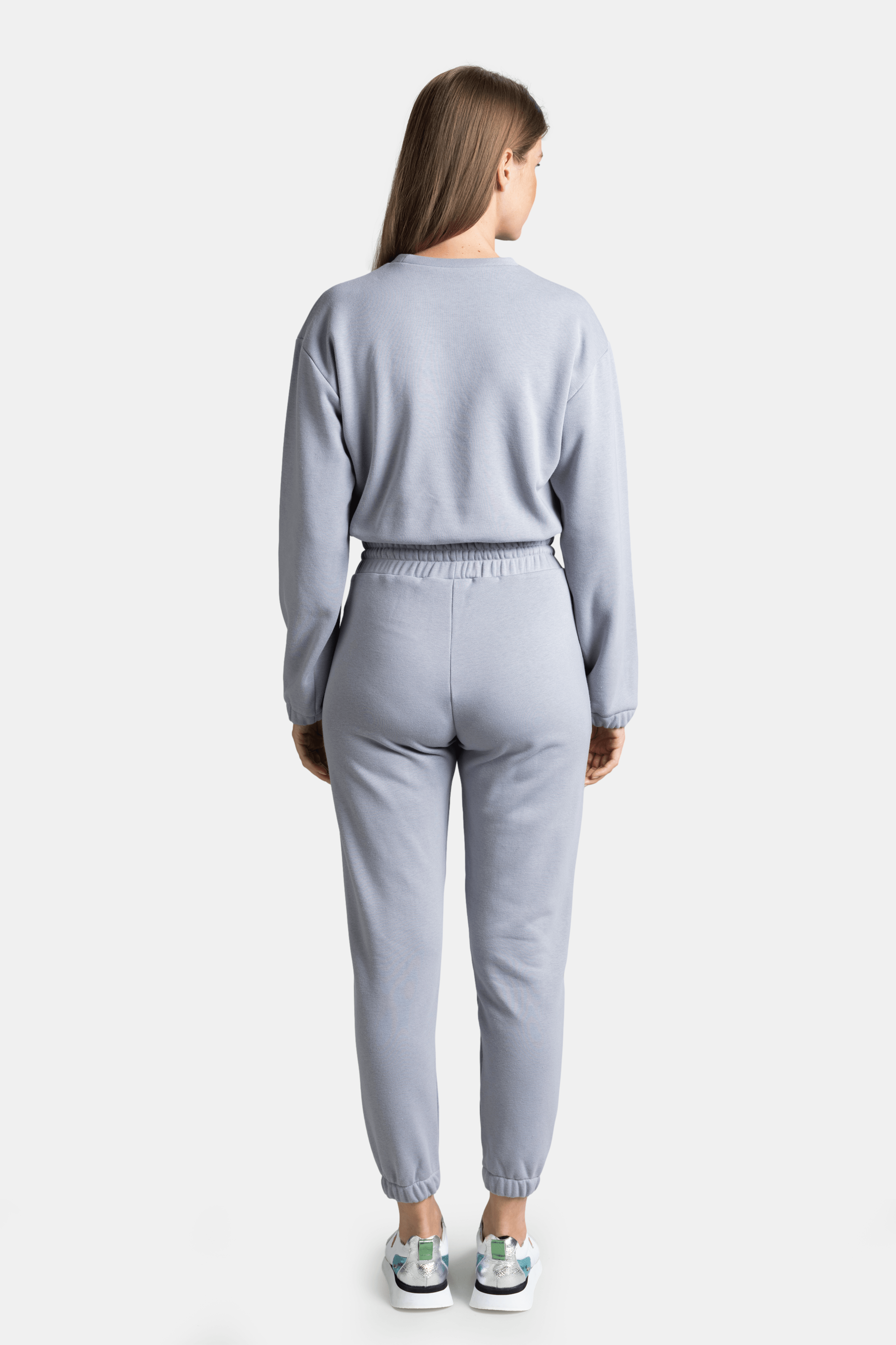 Woman in light gray NOWIHT tracksuit set, back view, with relaxed posture.