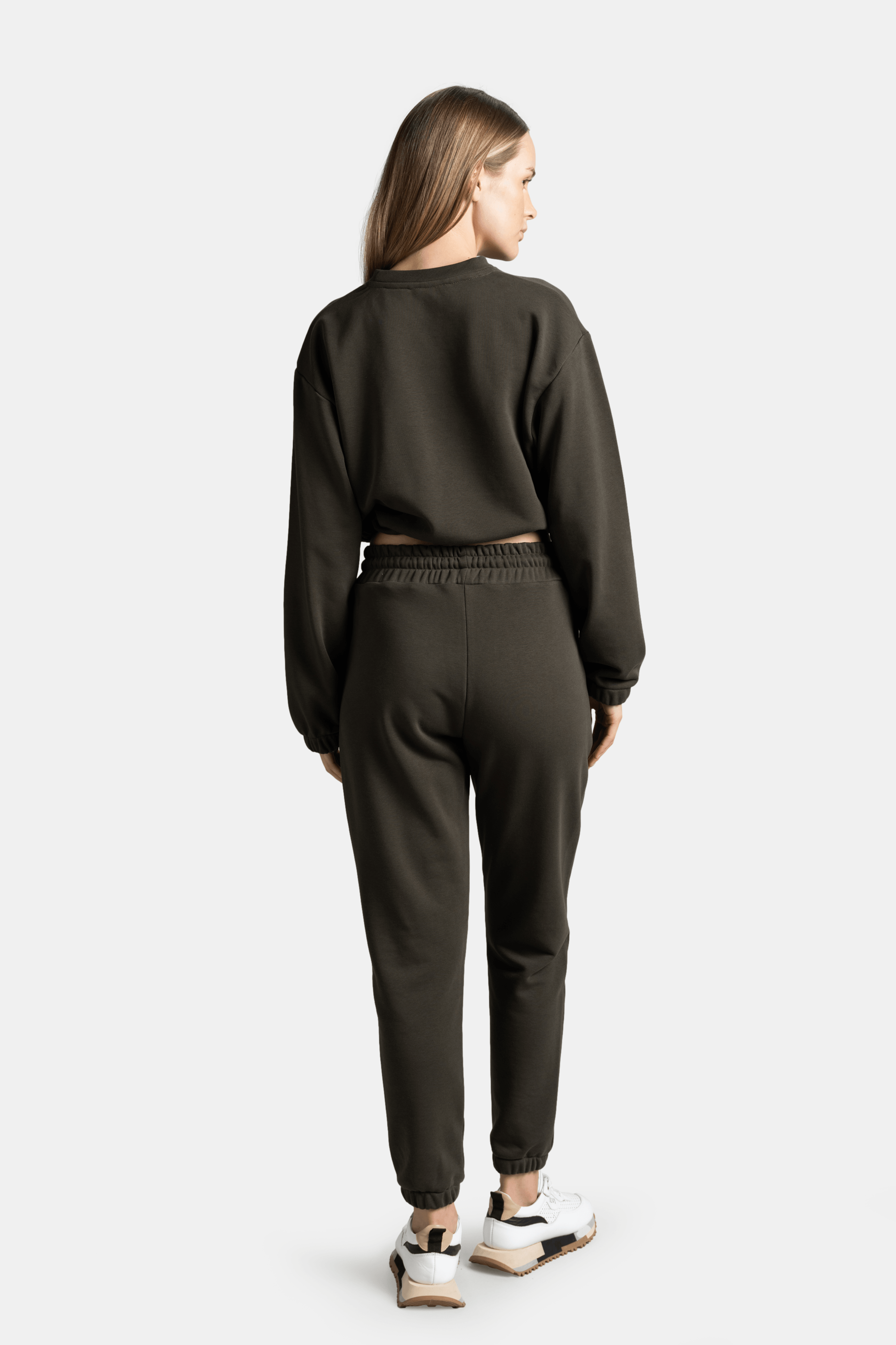 Back view of a model wearing a dark green sweatshirt and jogger pants, highlighting the fit and style of the set.