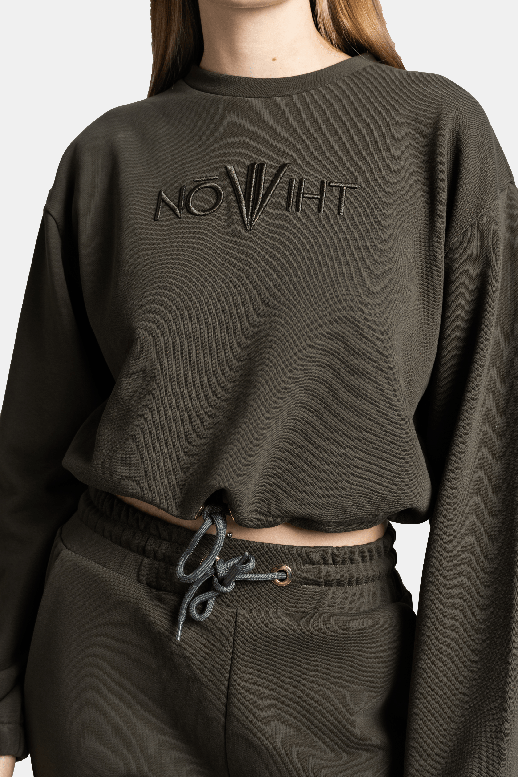 Detail shot of the dark green sweatshirt and jogger pants, focusing on the drawstring waistband and relaxed crop top fit.