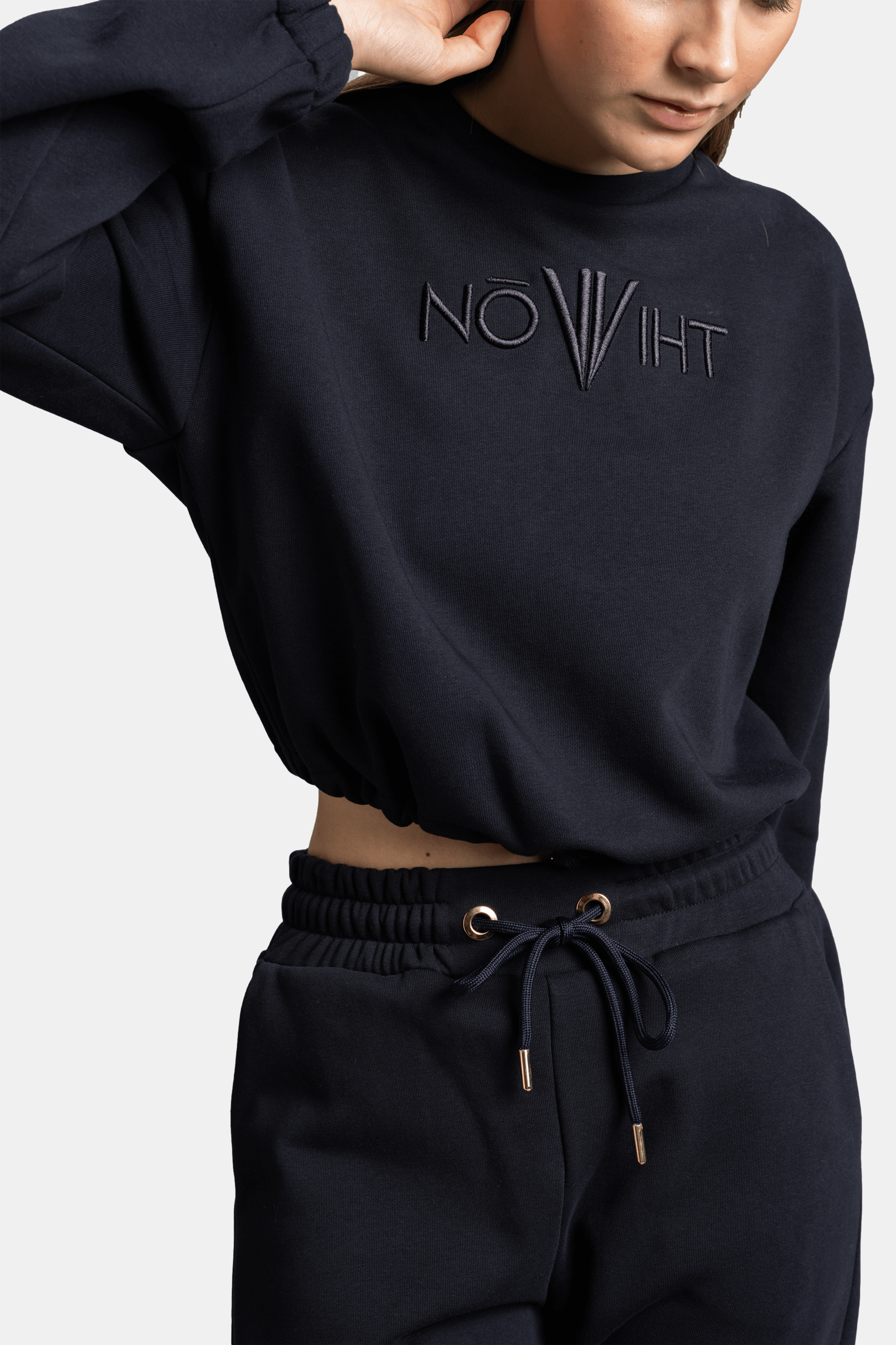 Detailed view of the black tracksuit top with embossed logo, showcasing the fabric texture and design on the front.