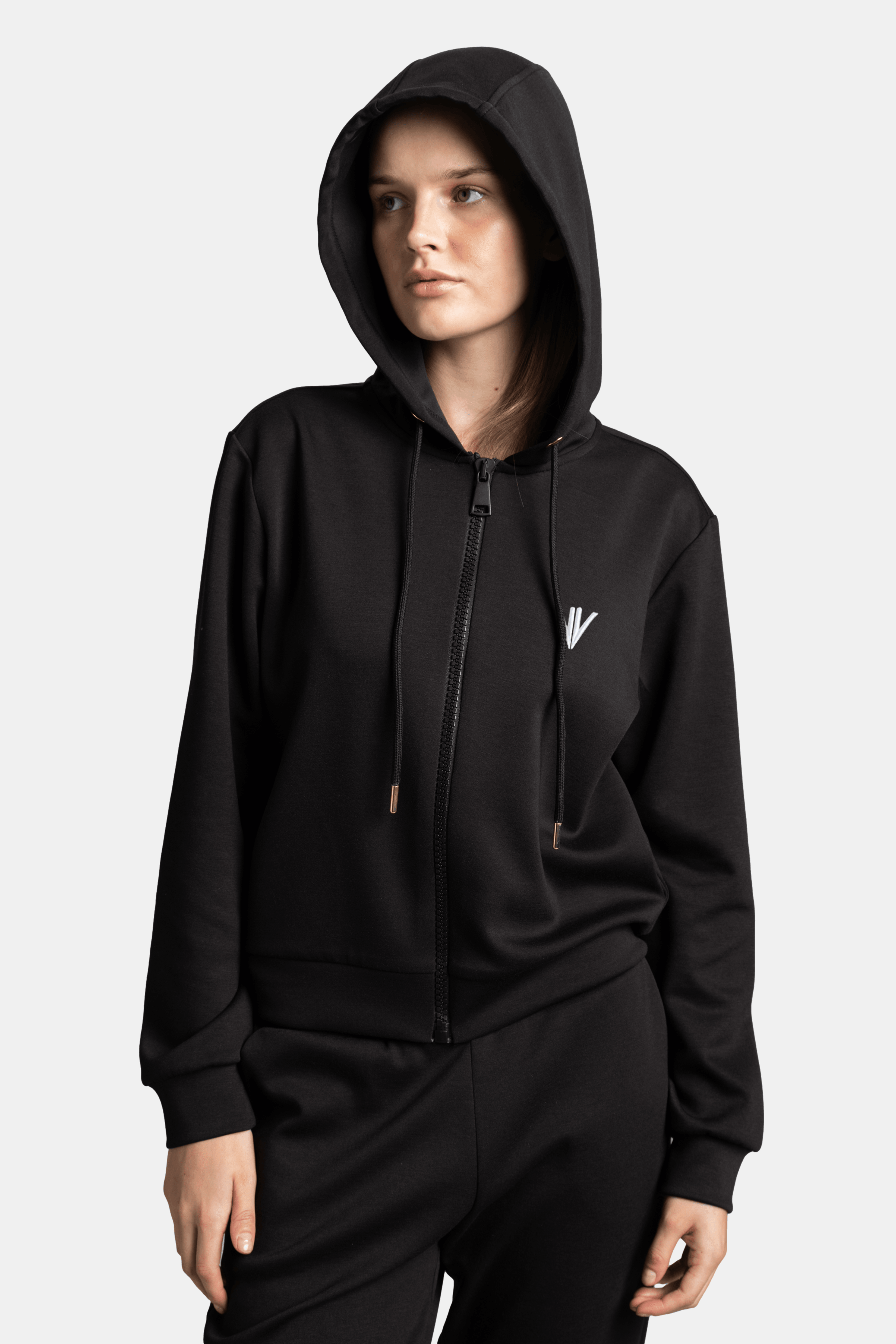 Close-up of the woman in a black hoodie with the hood up, looking slightly to the side, focusing on the hoodie’s drawstring details.