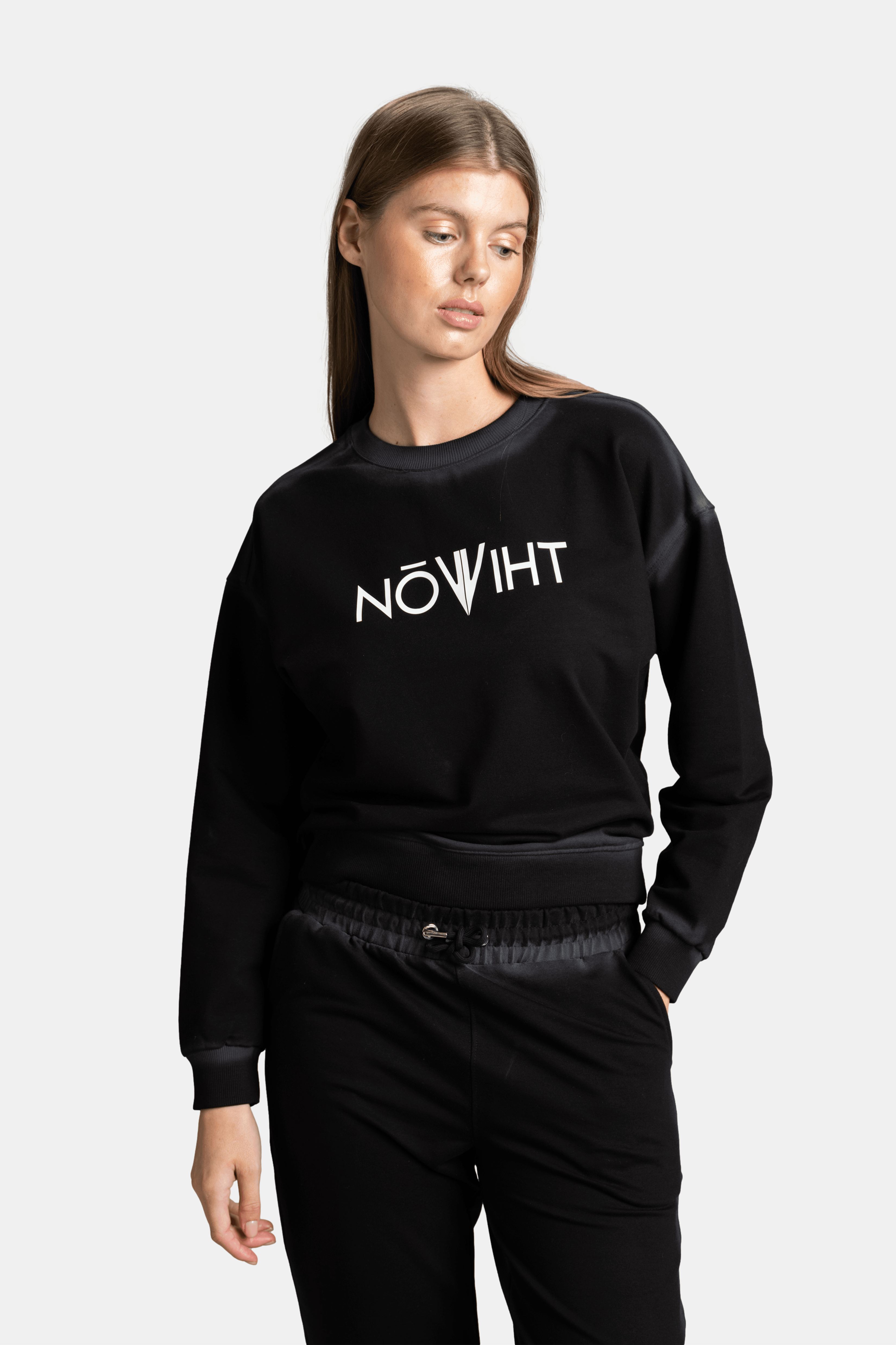 Slightly angled view of the model in a black sweatshirt with a white logo, standing with a relaxed posture.