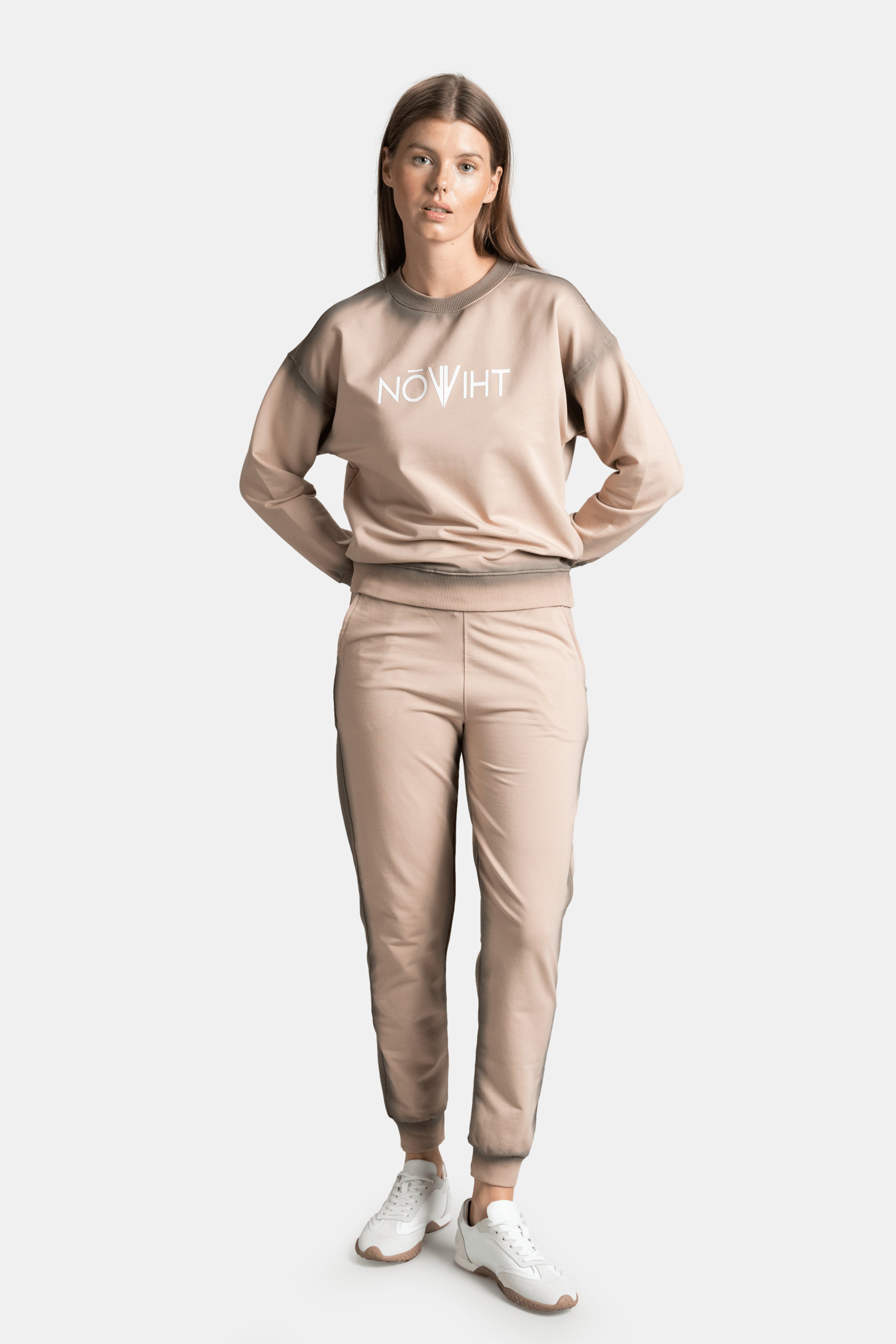 Front view of model standing with hands on hips in beige tracksuit, emphasizing the casual and comfortable fit.