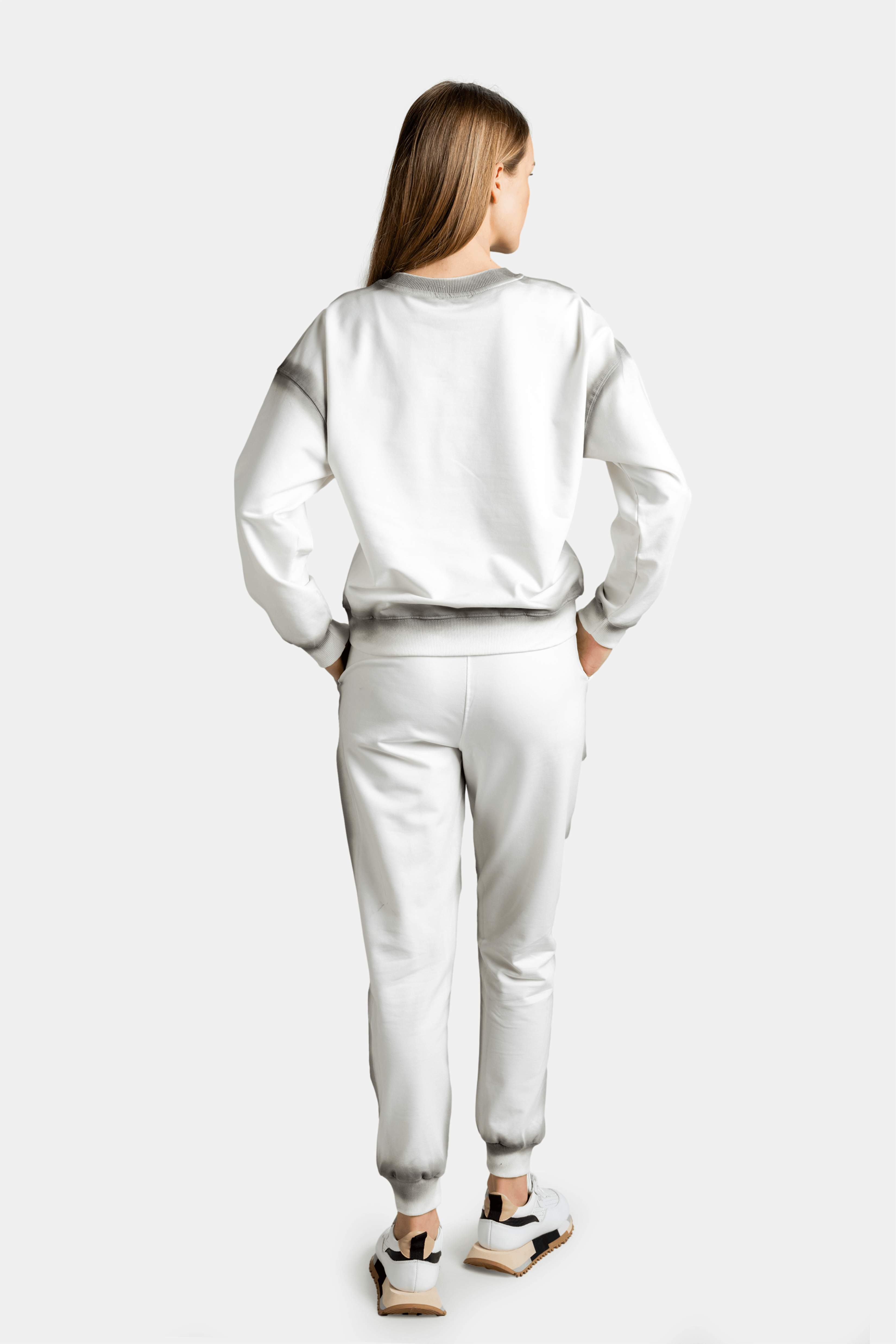 Rear view of the model in a light grey sweatsuit, showing the fit and detailing from behind.