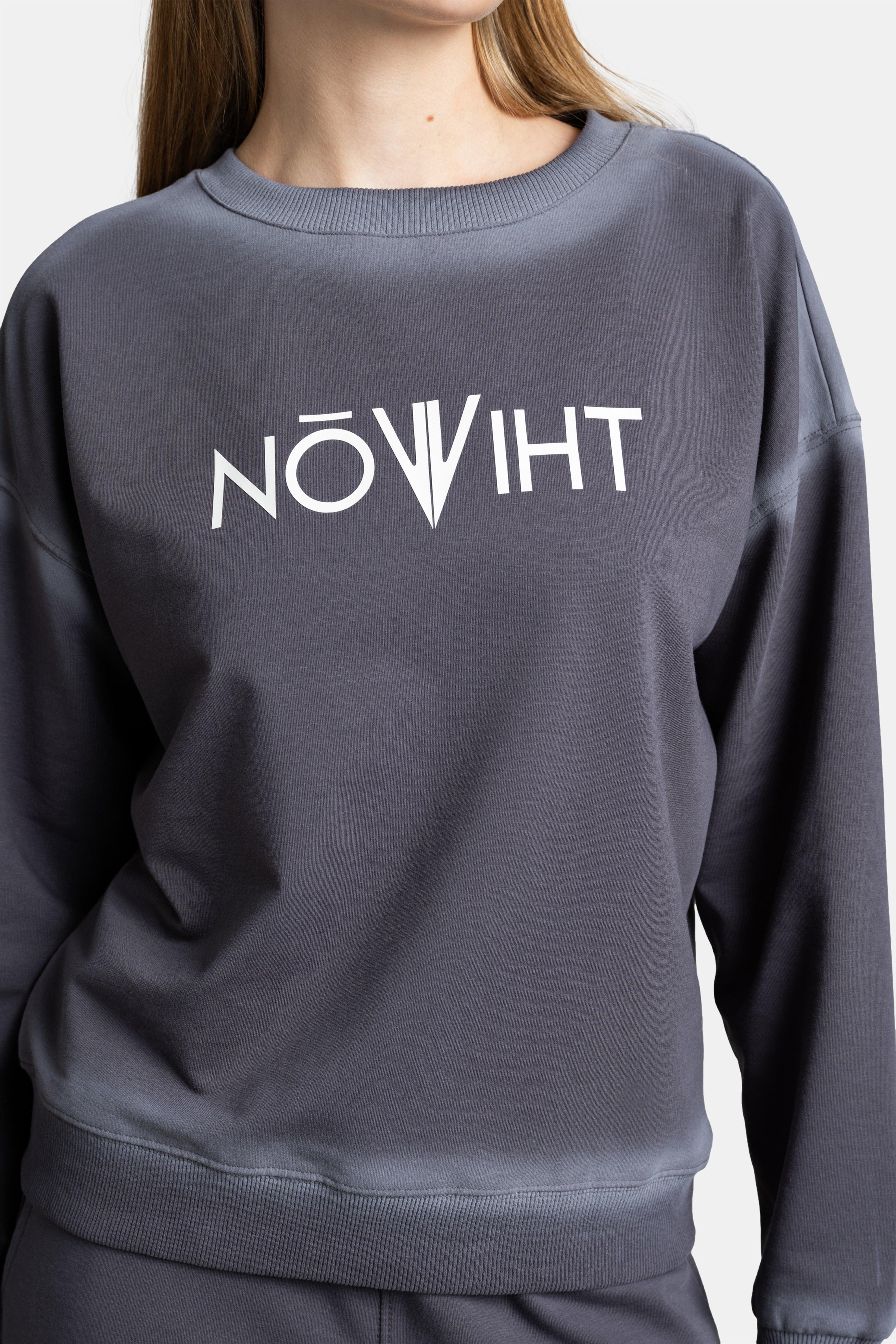 Detailed shot of the chest area of the dark gray sweatshirt, highlighting the logo design on the fabric.