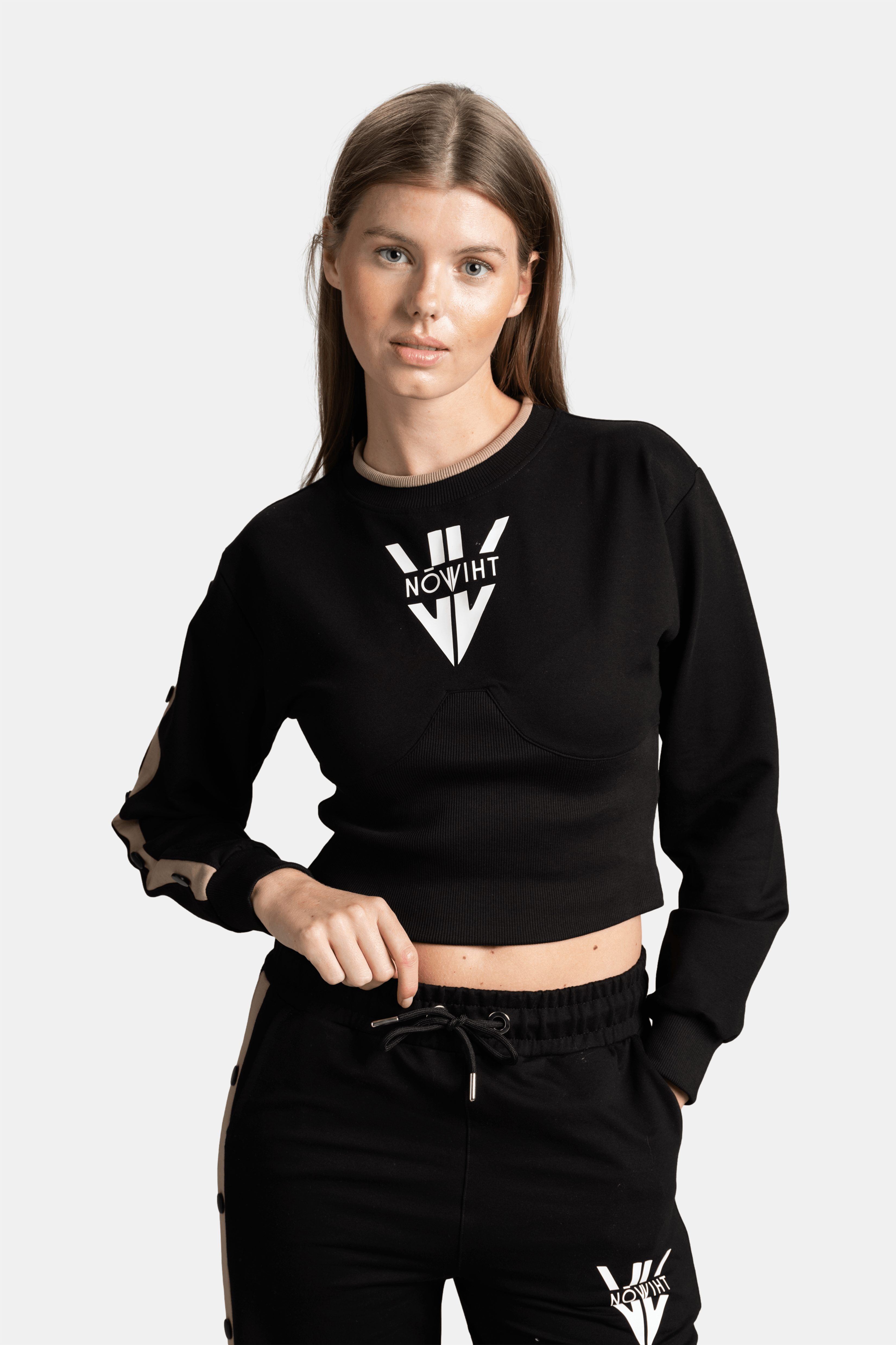 Close-up front view of a woman in a black cropped sweatshirt with a white logo on the chest.