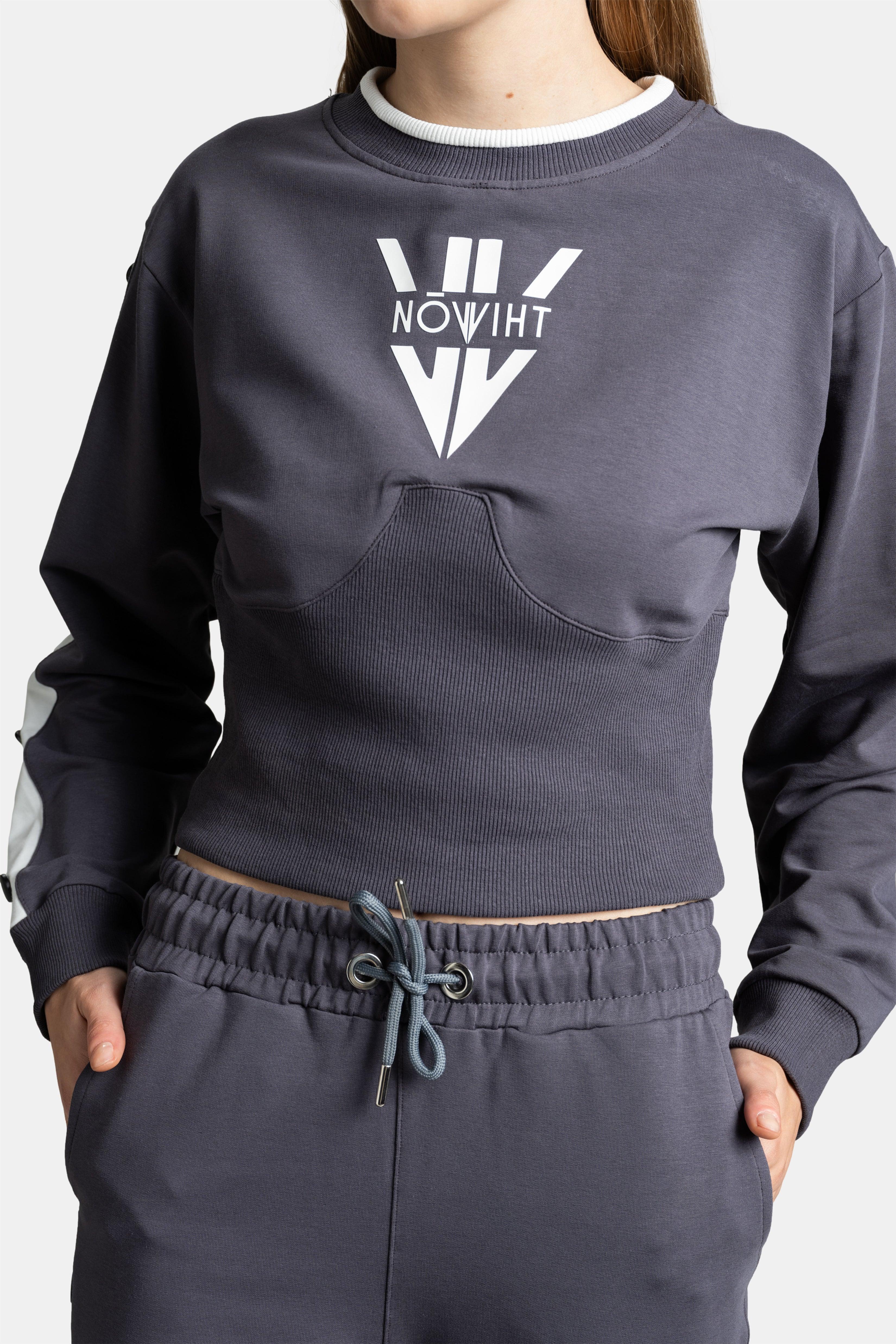 Close-up of the dark gray sweatshirt with a prominent white logo on the chest, showing ribbed detailing.