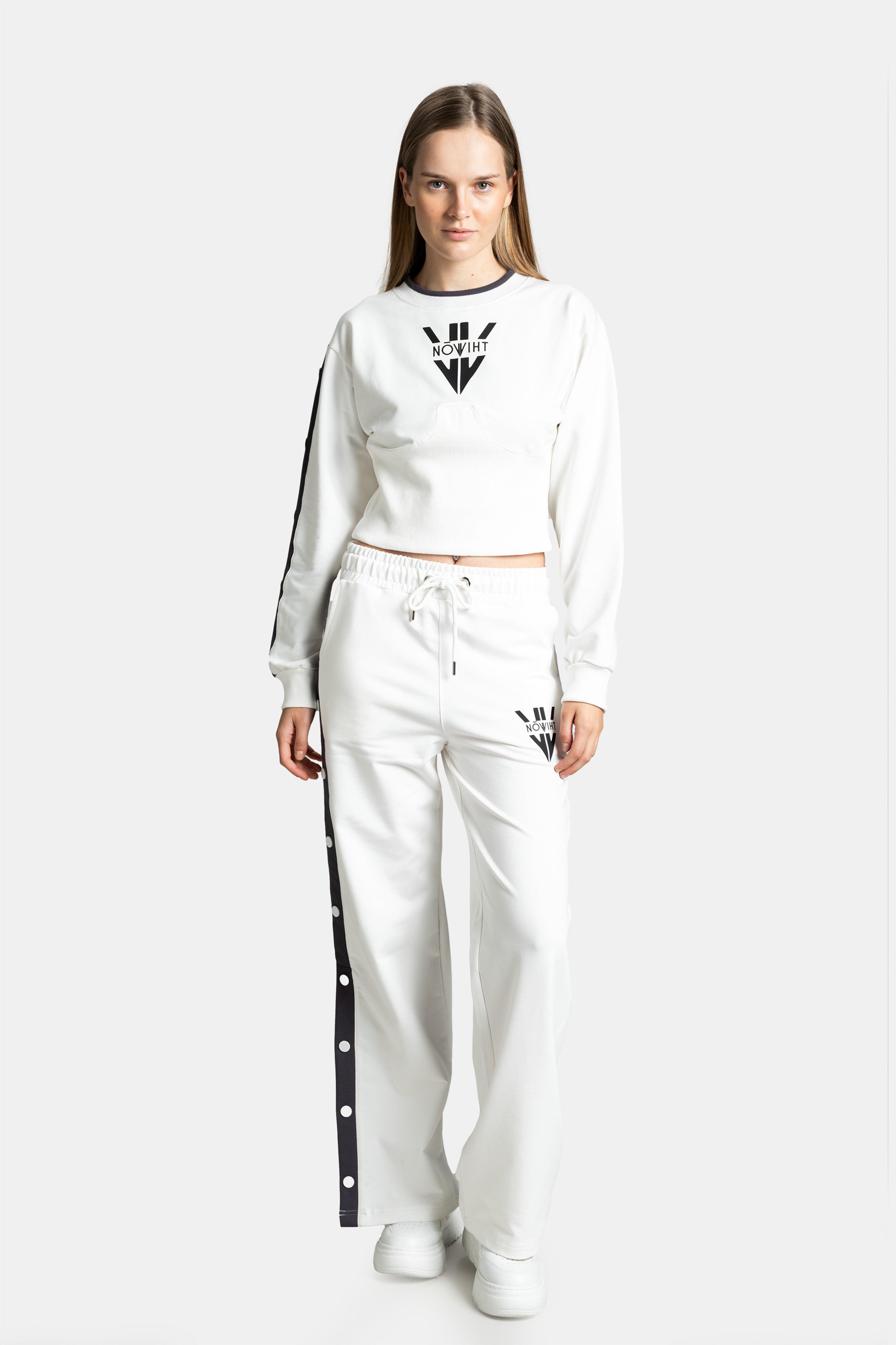 Front view of a model wearing a white tracksuit with black side stripes and snap details, standing with a neutral expression.