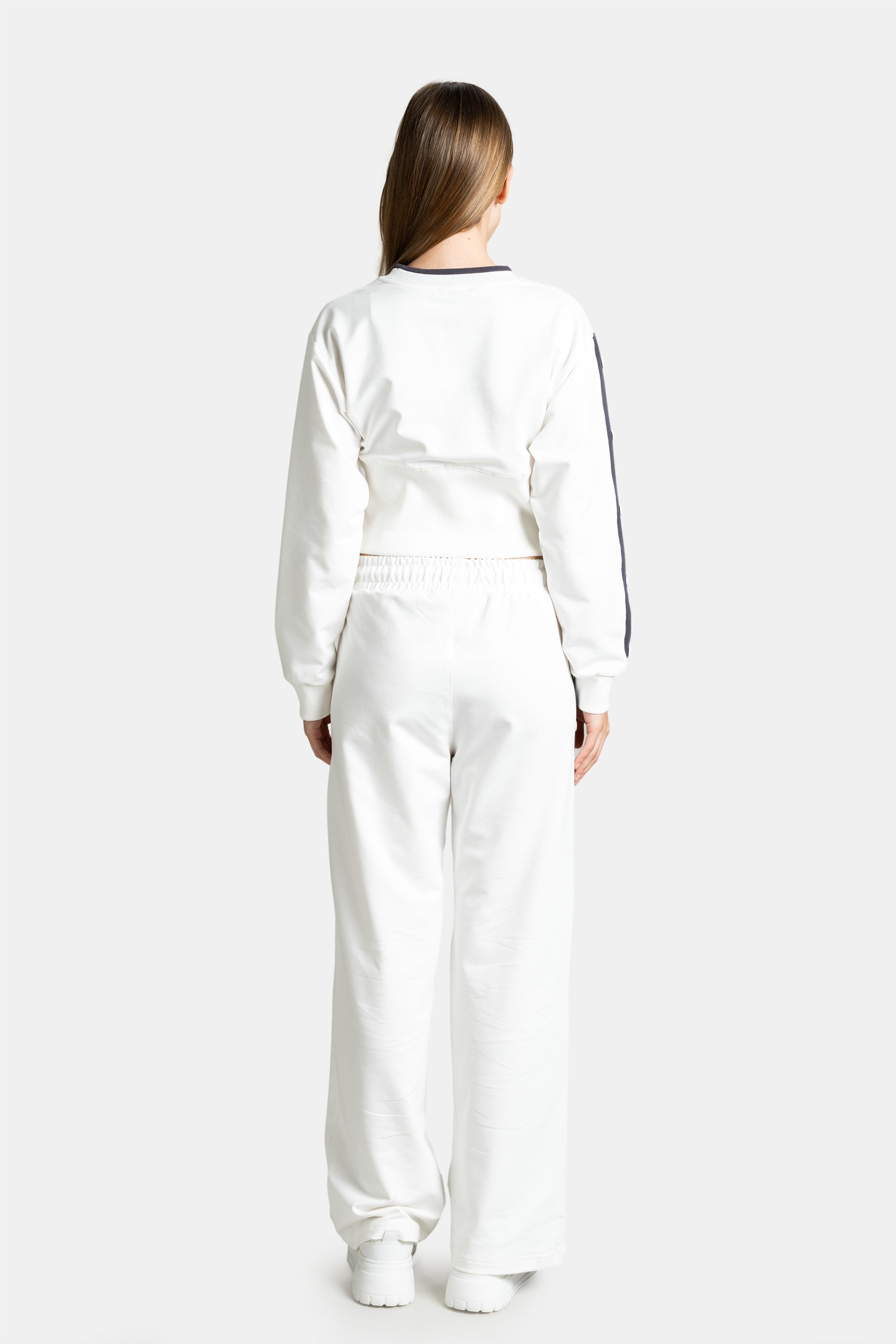 Back view of the model in a white tracksuit, showcasing the full length of the pants and back of the sweatshirt.