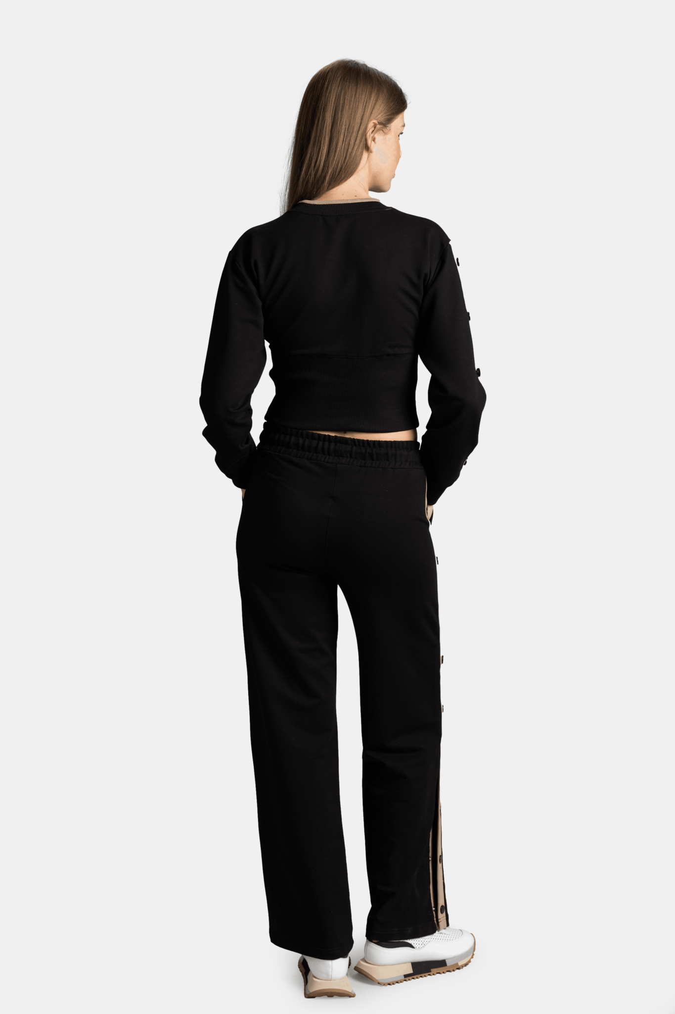 Rear view of a woman in a black cropped sweatshirt and wide-leg pants, highlighting the comfortable fit and relaxed style.